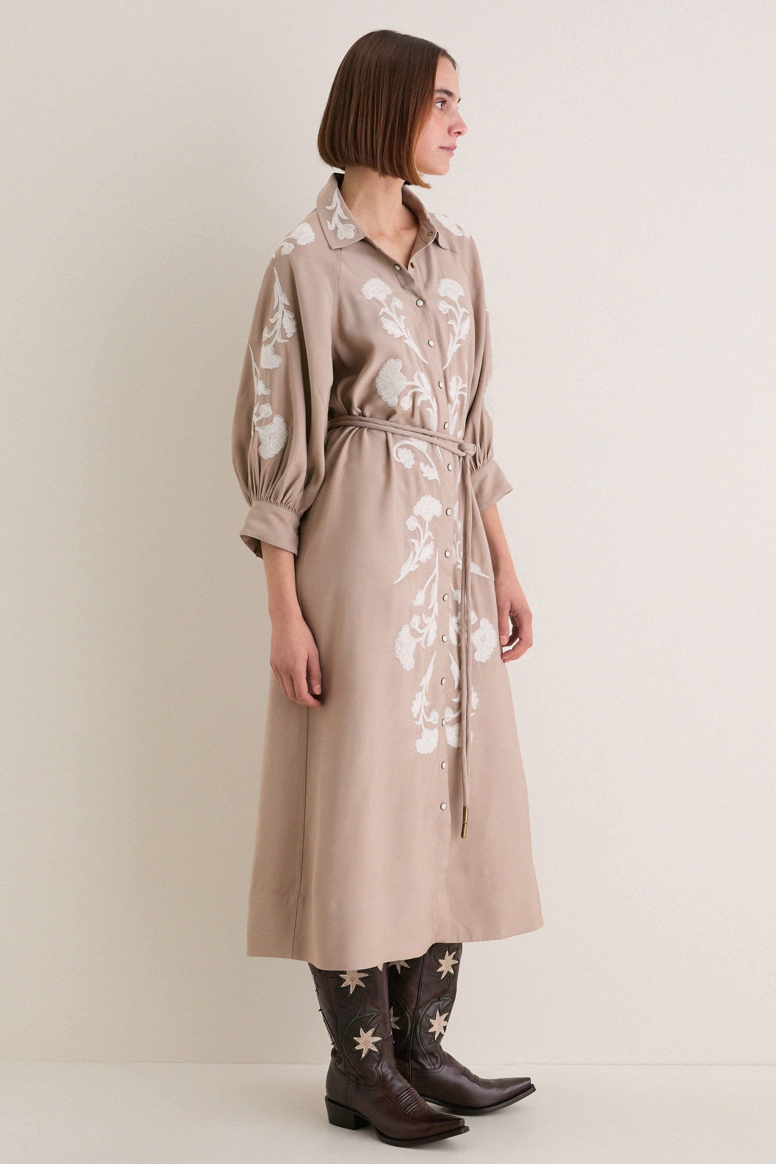 Woman in profile wearing a classic Soft Tan Western Embroidered Herd Dress with floral embroidery, puffed sleeves, and cowboy boots, embodying effortless, high-end style.