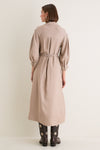 Woman in a classic Soft Tan Western Embroidered Herd Dress with a belted waist and billowed sleeves, paired with star-embroidered cowboy boots, radiating effortless, high-end style.
