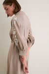 Woman in profile wearing the classic, high-end Soft Tan Western Embroidered Herd Dress with bishop sleeves and floral embroidery, exuding effortless and fun style.