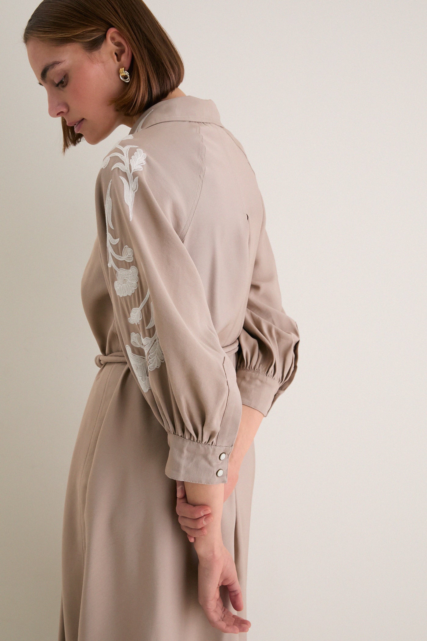 Woman in profile wearing the classic, high-end Soft Tan Western Embroidered Herd Dress with bishop sleeves and floral embroidery, exuding effortless and fun style.