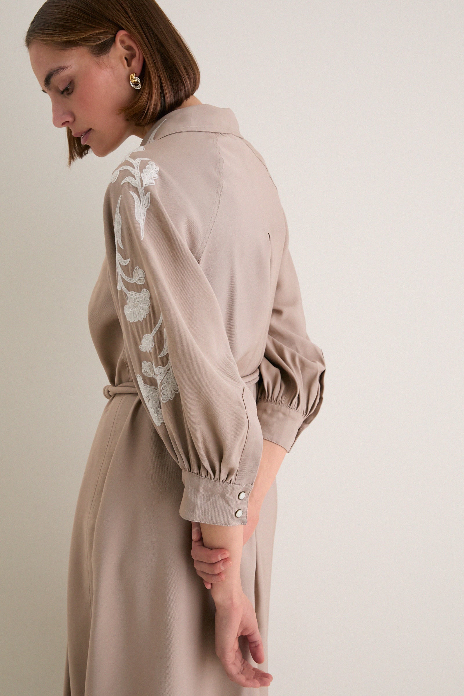 Woman in profile wearing the classic, high-end Soft Tan Western Embroidered Herd Dress with bishop sleeves and floral embroidery, exuding effortless and fun style.