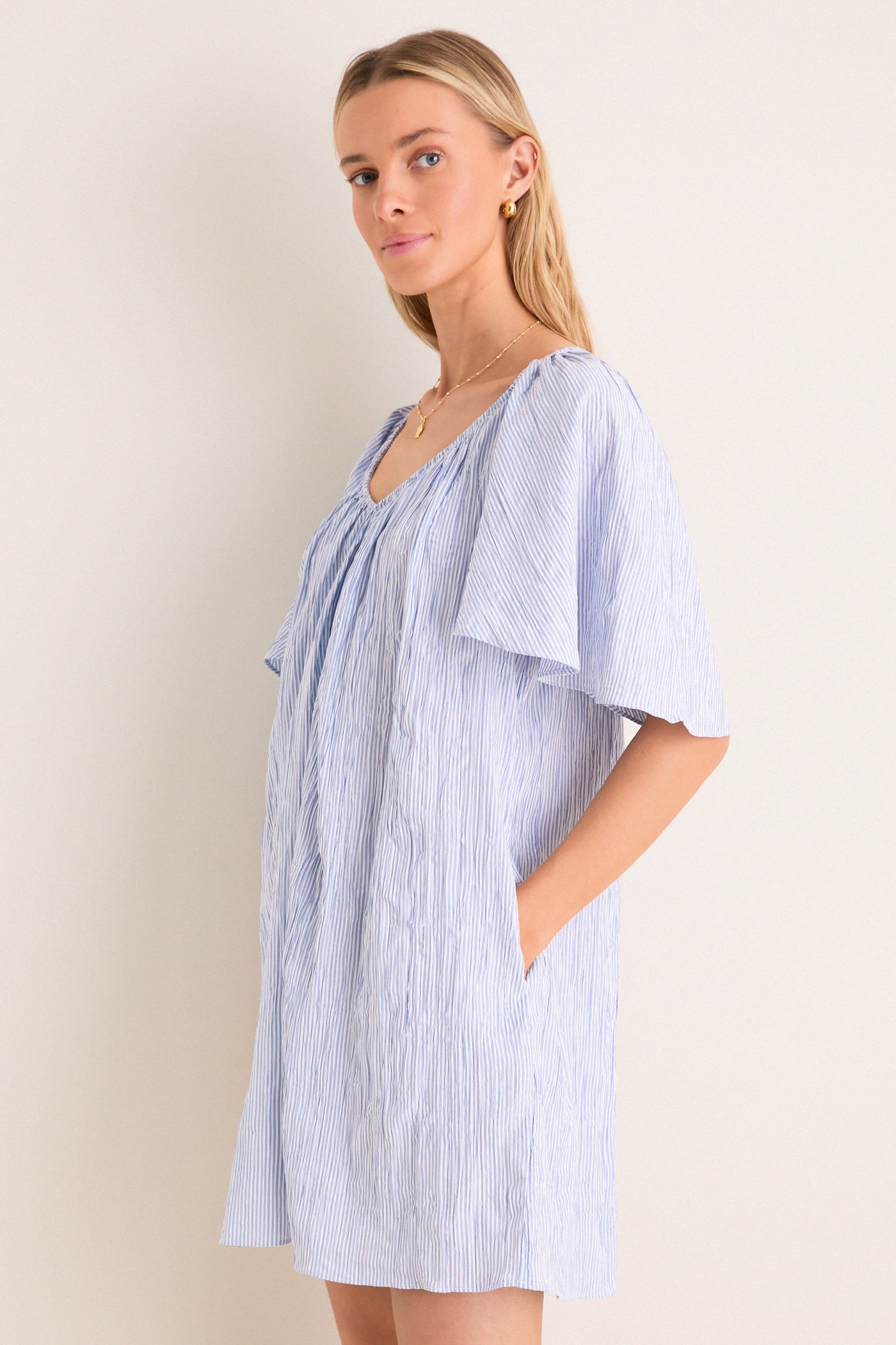 Young woman in a classic, effortless Saltwater Stripe Finn Dress with flutter sleeves and pockets, embodying a fun, high-end style suitable for any adventure.