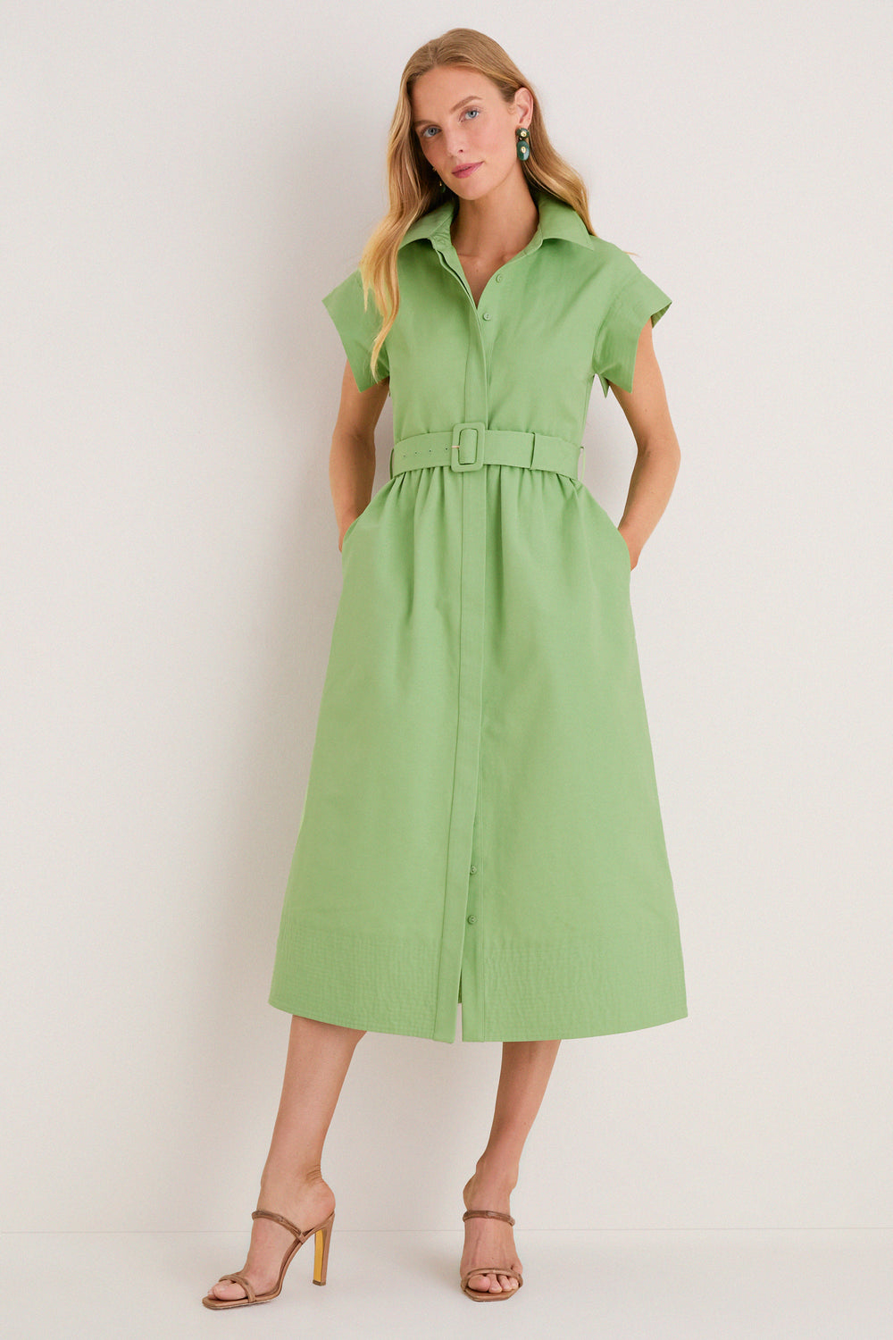 Model wearing the classic Pistachio Chloe Dress, featuring a button-front, cap sleeves, and a matching belt. Paired with beige strappy sandals for an effortless, high-end look.