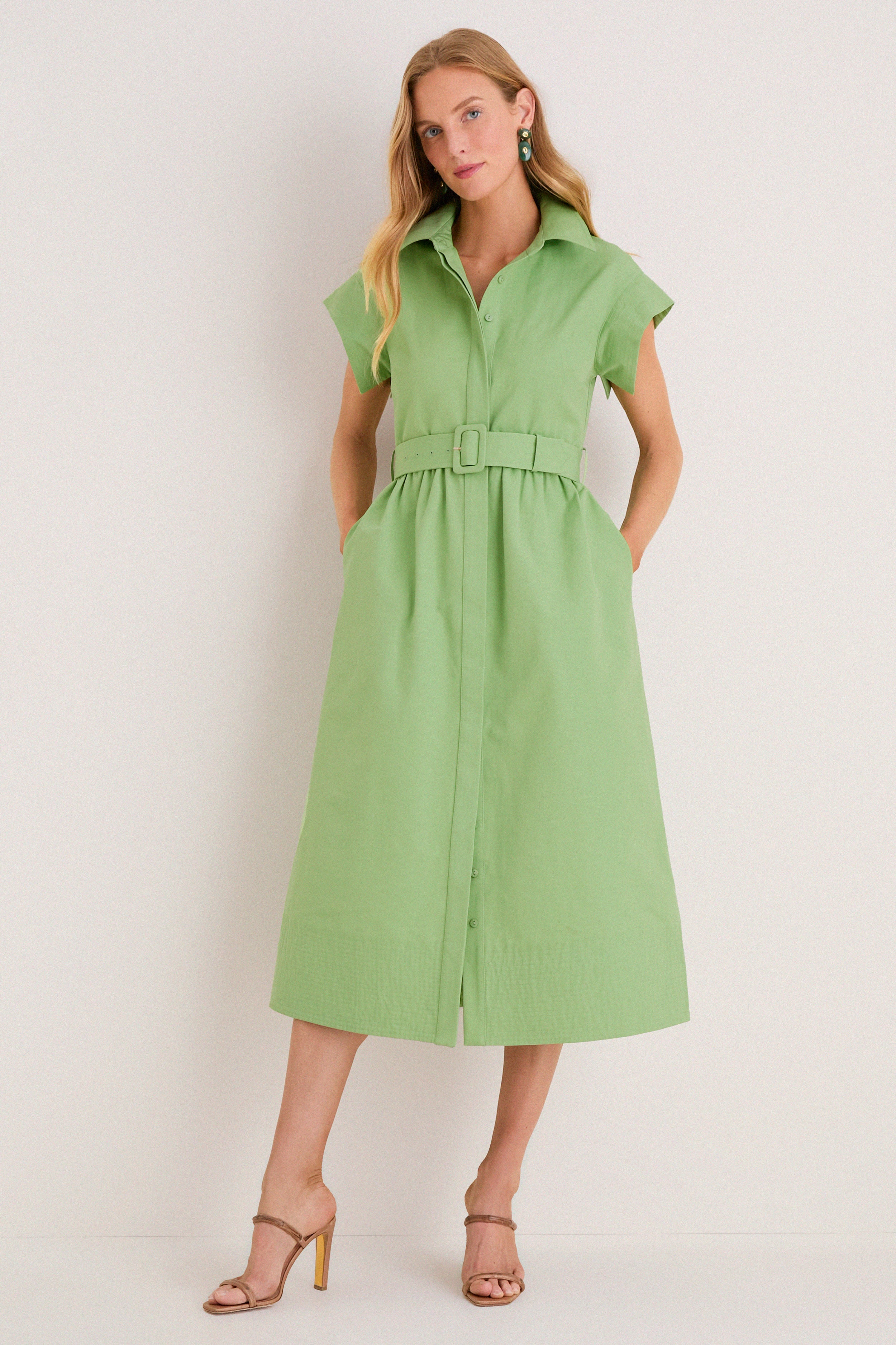 Model wearing the classic Pistachio Chloe Dress, featuring a button-front, cap sleeves, and a matching belt. Paired with beige strappy sandals for an effortless, high-end look.