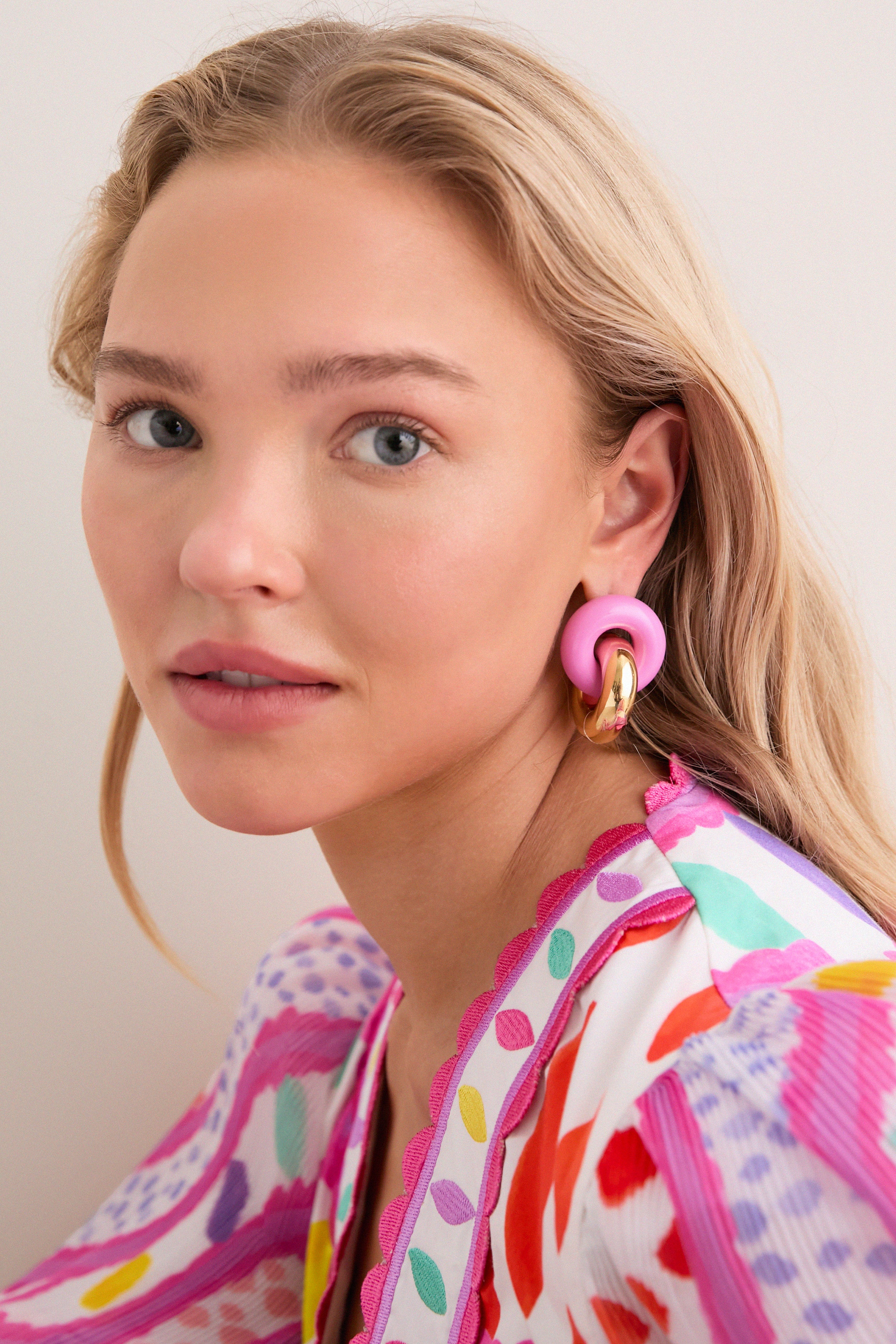 Young woman with blonde hair wearing classic, fun Cotton Candy and Gold Cumulus Earrings, featuring chunky gold hoops and pink elements, showcasing an effortless, high-end style.