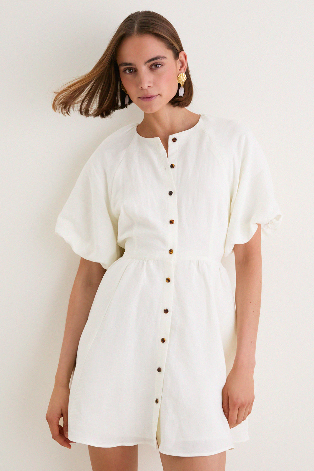 Model in a classic, effortless Bastille Short Dress with puffed sleeves and button placket, embodying a high-end, fun aesthetic perfect for versatile, leisurely weekends.