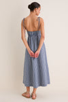 Back view of a woman in the classic Navy Gingham Sloan Maxi Dress with tie straps, showcasing its effortless and fun smocked back and elegant silhouette.