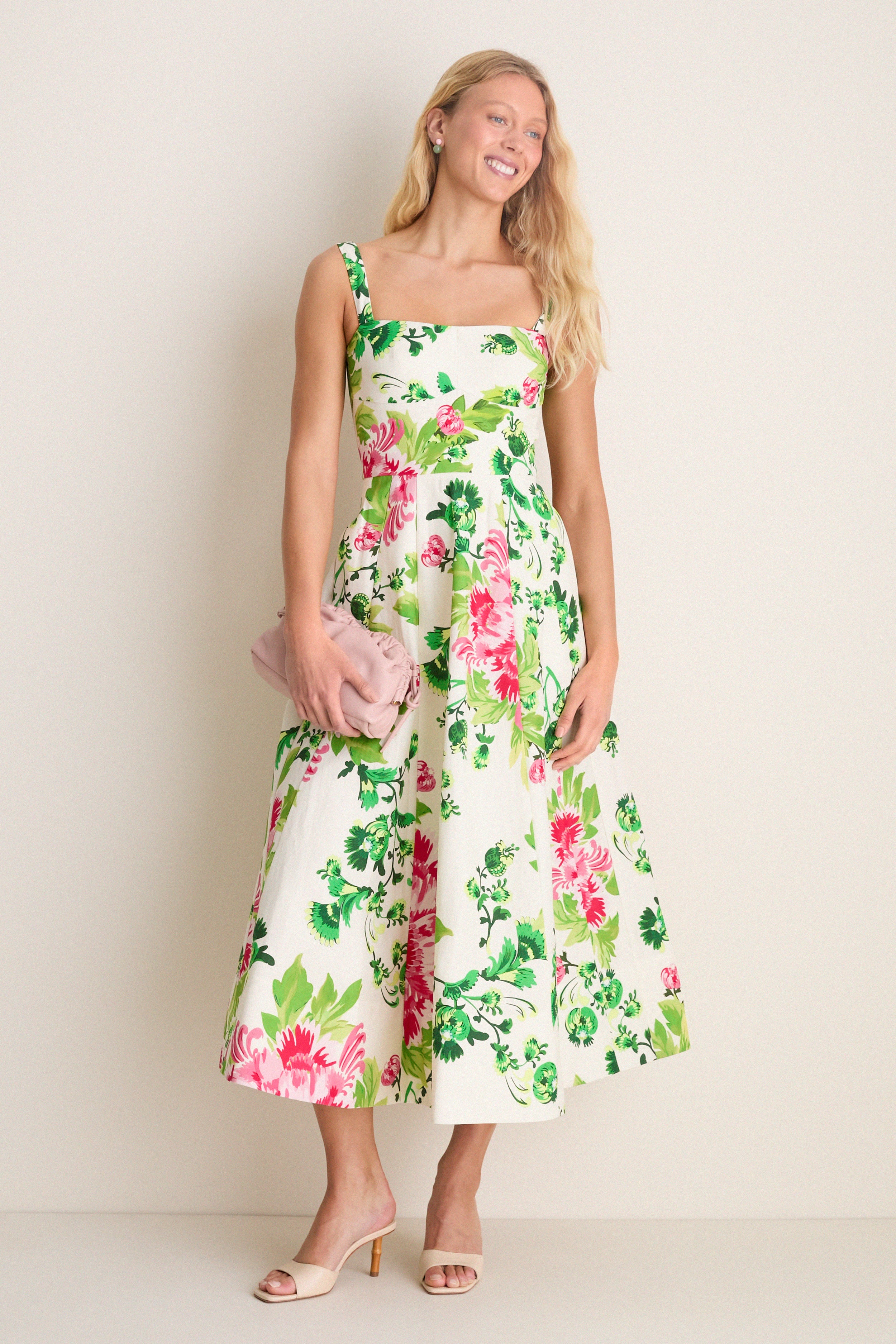 Saffier Bouquet Sabrina Midi Dress: A classic, effortless midi with bold floral print, square neckline, and flared skirt. Paired with a pink clutch and nude heeled mules.