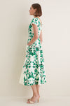 Woman in profile wearing the classic Saffier Vines Zoey-E Midi Dress with green vine motifs, cap sleeves, and beige mule heels, exuding effortless, high-end elegance.