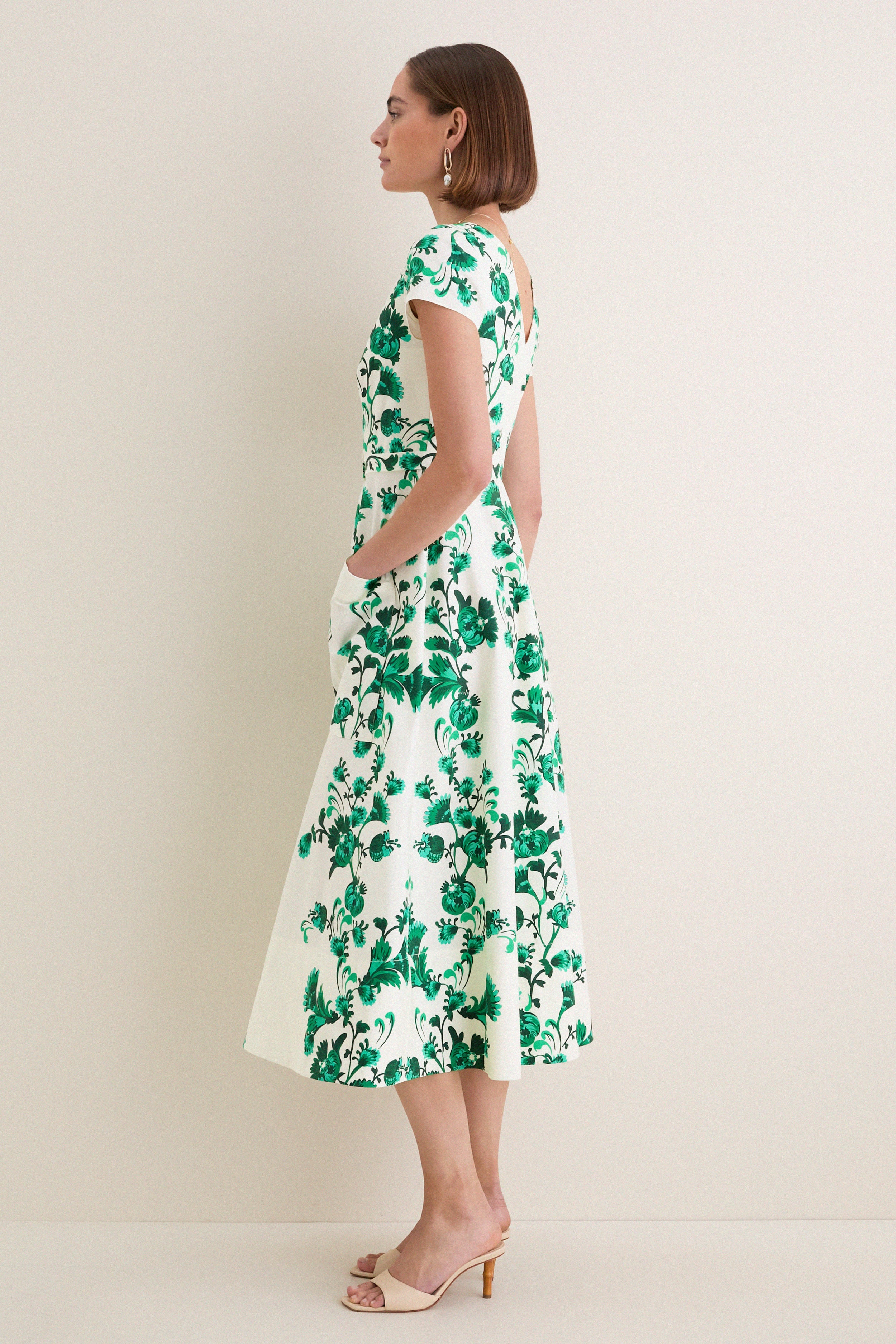 Woman in profile wearing the classic Saffier Vines Zoey-E Midi Dress with green vine motifs, cap sleeves, and beige mule heels, exuding effortless, high-end elegance.
