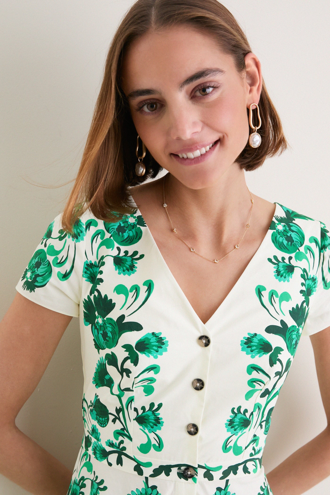 Saffier Vines Zoey-E Midi Dress: A classic, effortless white dress with green floral print, V-neck, button front, and playful accessories, embodying Tuckernuck's high-end, fun style.