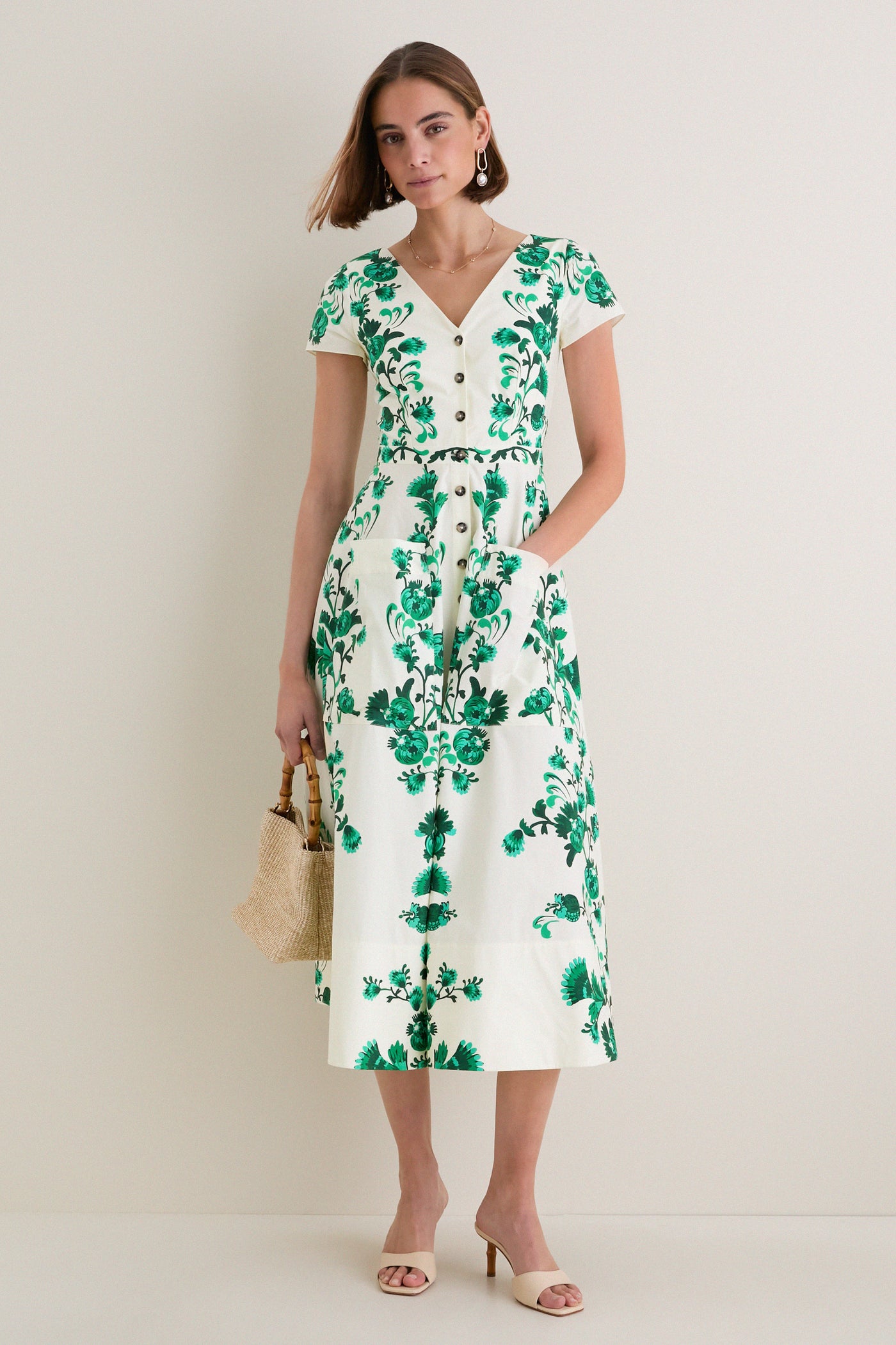 Saffier Vines Zoey-E Midi Dress exudes classic elegance with its green floral print, button-down front, and fitted waist, paired effortlessly with chic accessories for a high-end, fun look.