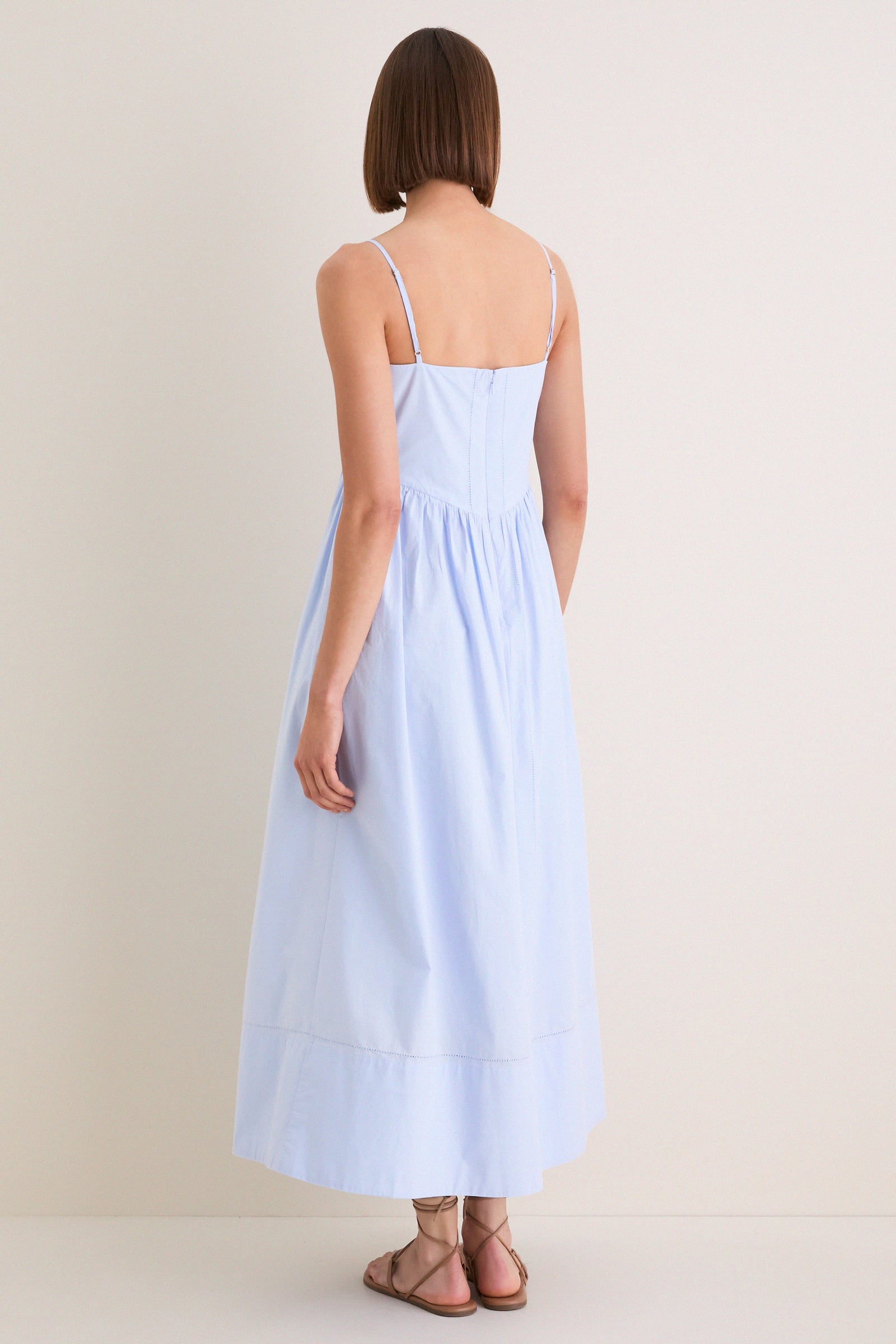 Rear view of model in French Blue Peninsula Dress, featuring classic adjustable straps and effortless fit, embodying high-end style with a fun, romantic silhouette.