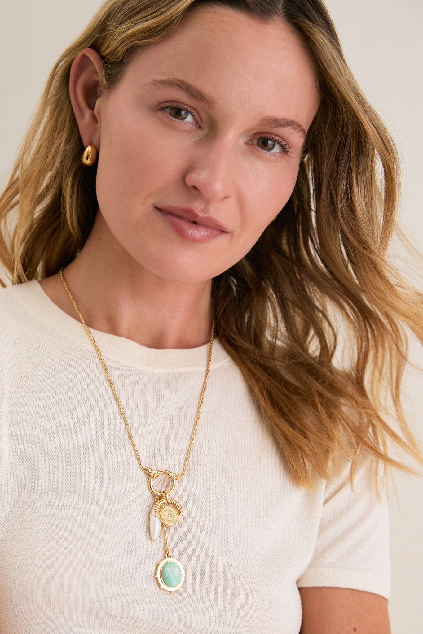 Woman wearing Gold Multi Frances Charm Necklace featuring classic gold chain with charms: mint-green medallion, pearl drop, sunburst. Effortless, high-end style perfect for fun, confident looks.