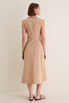 Woman in Khaki Orla Dress, a classic, effortless shirtdress with cap sleeves, side ruching, and a front slit, paired with black sandals and gold accessories.