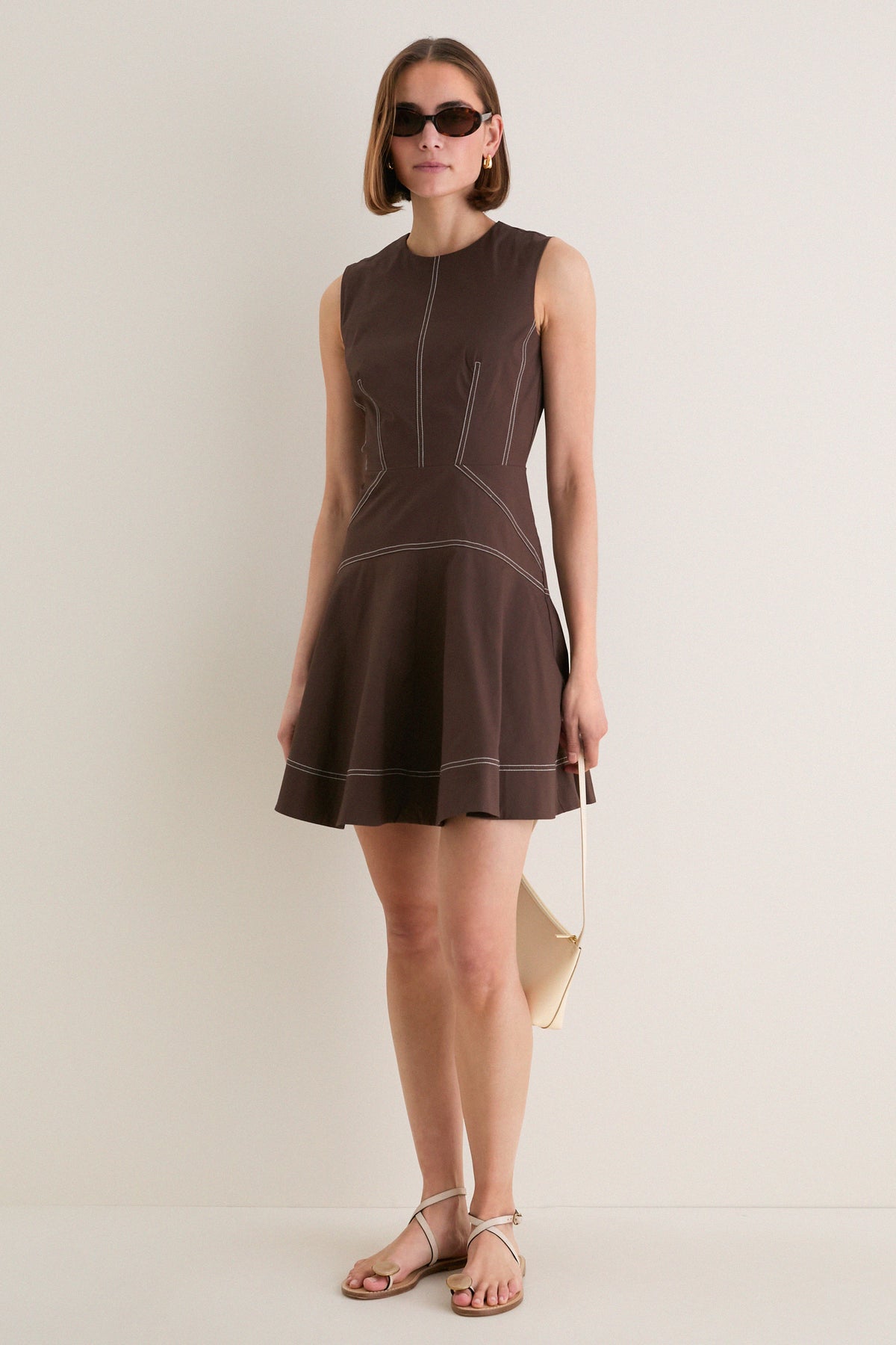 Young woman models the Dark Mocha Mini Karrigan Dress, showcasing its classic fit-and-flare silhouette, fun contrast topstitching, and effortless high-end style.