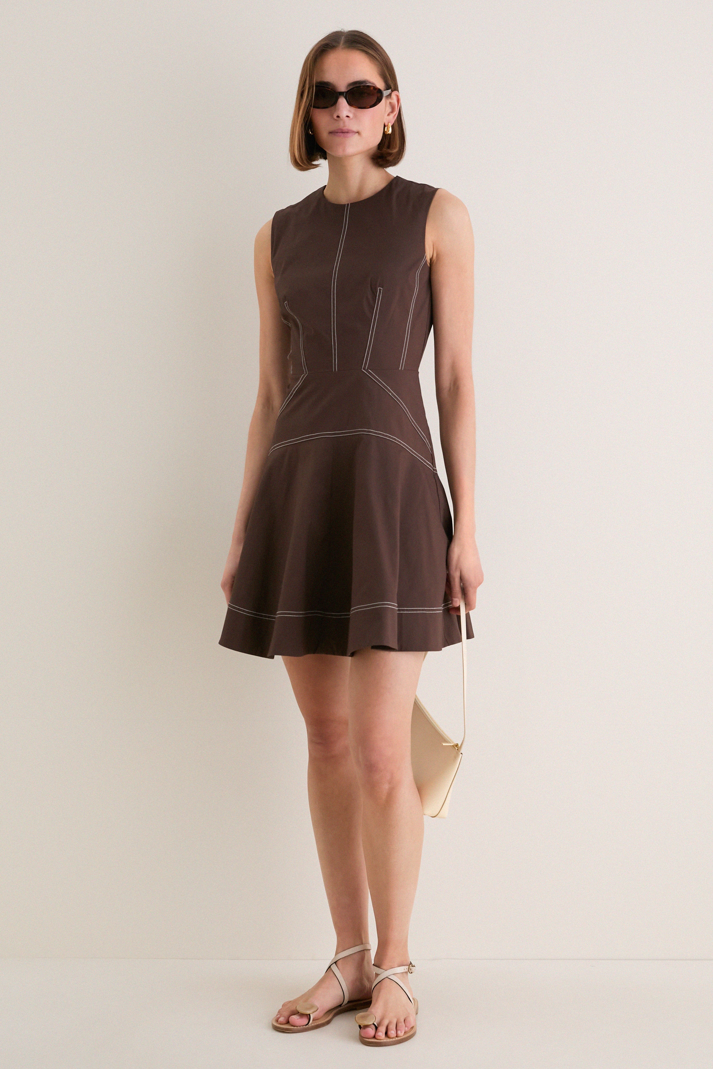 Young woman models the Dark Mocha Mini Karrigan Dress, showcasing its classic fit-and-flare silhouette, fun contrast topstitching, and effortless high-end style.