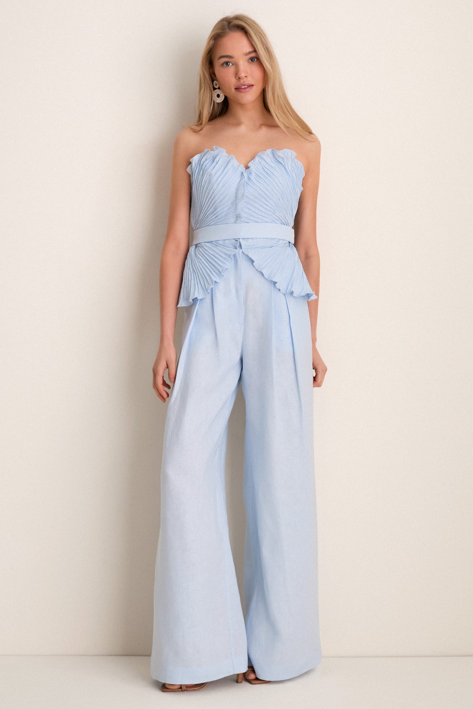 Young woman models the Baby Blue De Tres Embellished Top, a classic strapless linen piece with a sweetheart neckline and peplum hem, paired effortlessly with matching trousers.
