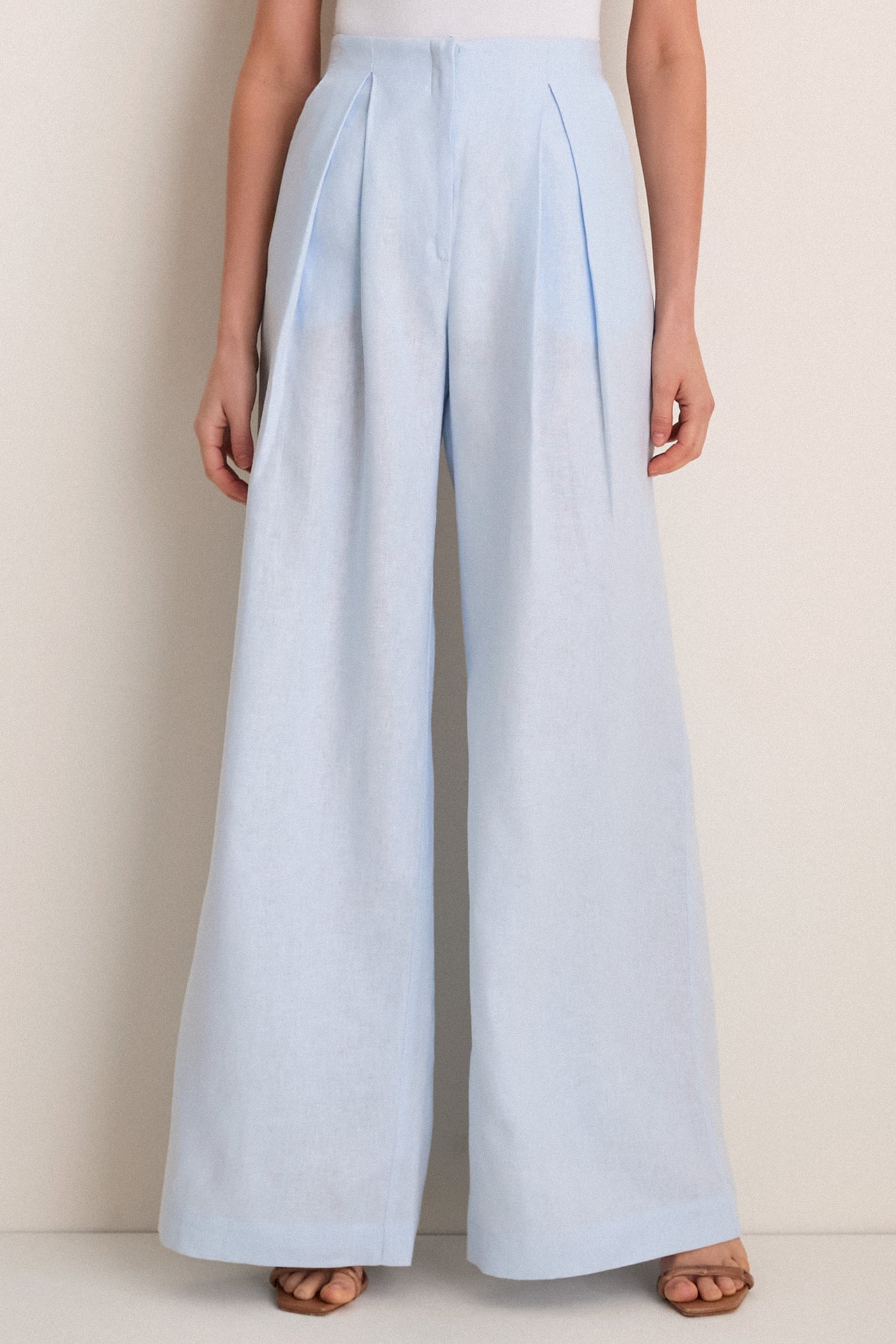 Classic Baby Blue Naces Tu Pants in high-rise, wide-leg silhouette with front pleats, styled with tan sandals. Effortless, high-end look for versatile occasions.