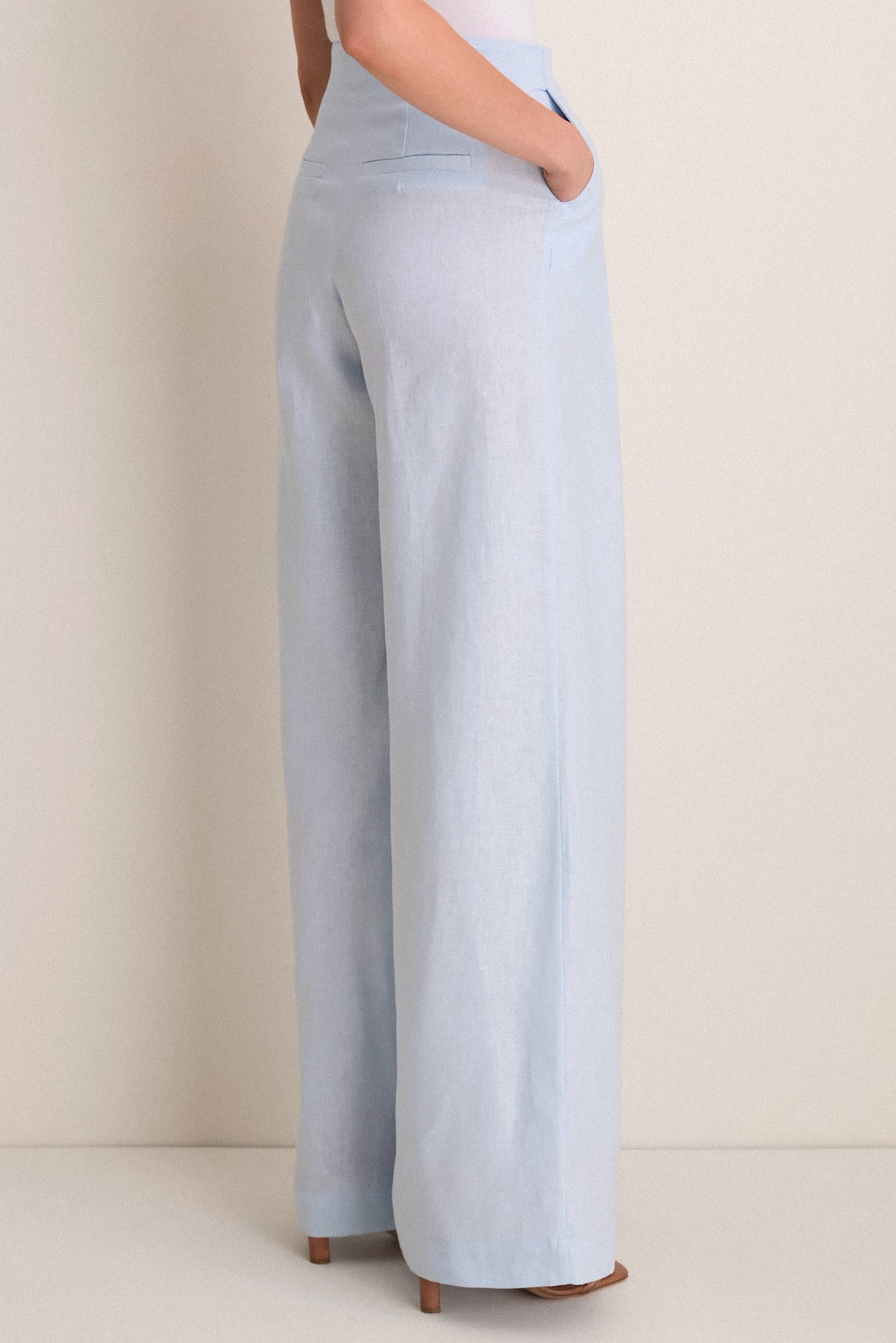 Person wearing Baby Blue Naces Tu Pants, showcasing classic high-rise, wide-leg design with effortless elegance, paired with tan block-heel sandals for a fun, high-end look.