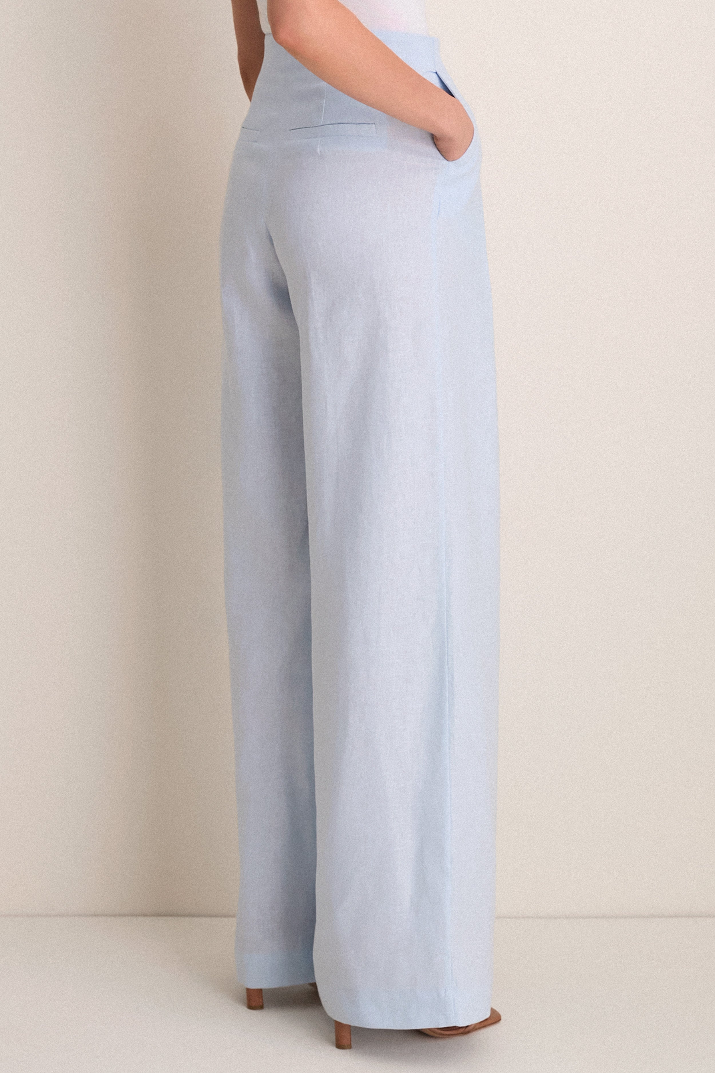 Person wearing Baby Blue Naces Tu Pants, showcasing classic high-rise, wide-leg design with effortless elegance, paired with tan block-heel sandals for a fun, high-end look.