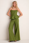 Woman models the Olive Green Oliva Profundo Top, a strapless, peplum linen piece paired with matching trousers, exuding classic elegance and effortless sophistication, perfect for high-end fashion.