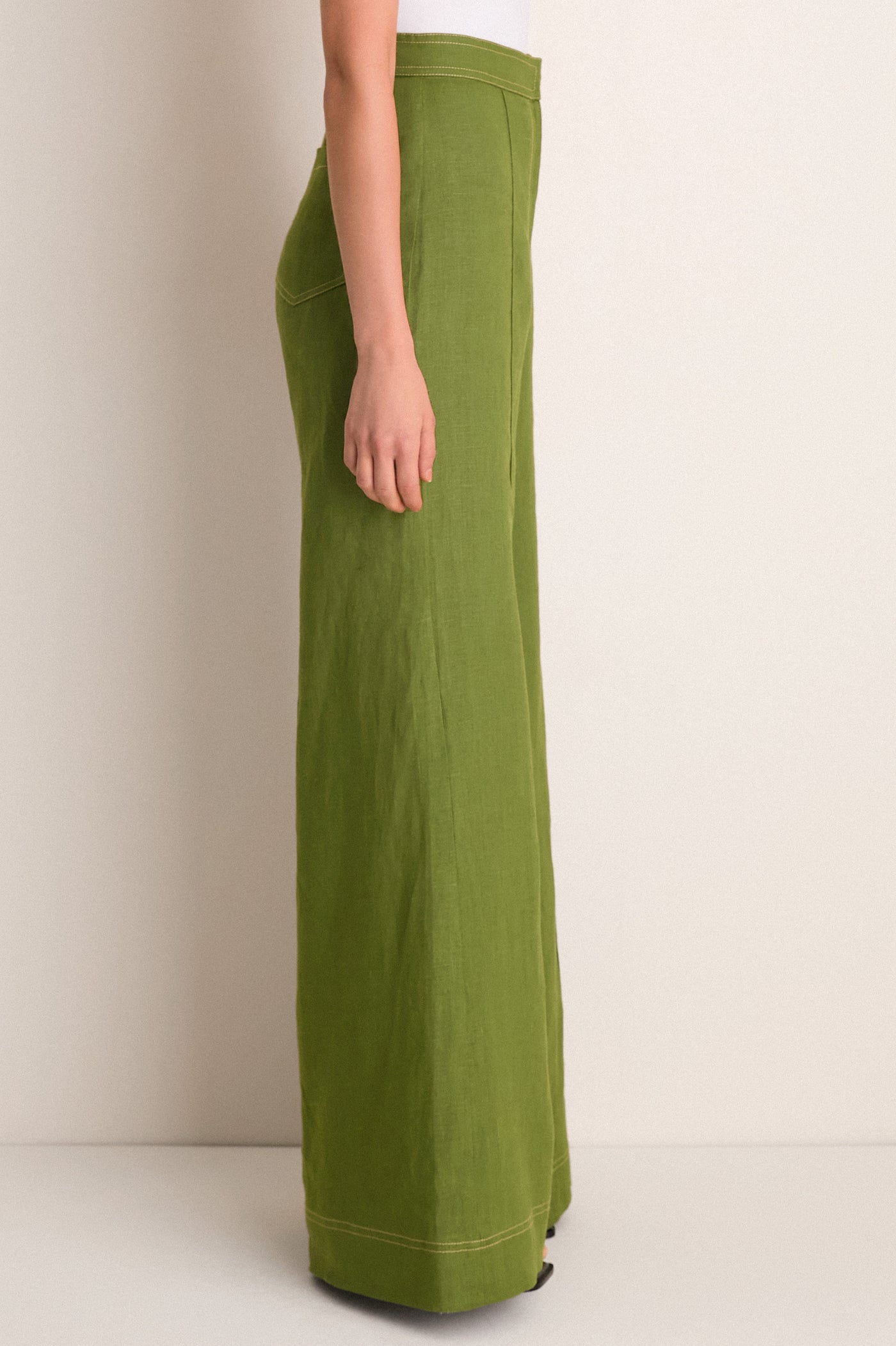 Profile view of Olive Green Vivir Pants showcasing a high-waisted, wide-leg cut with contrast stitching and back pocket detail, for an effortlessly classic, high-end look.