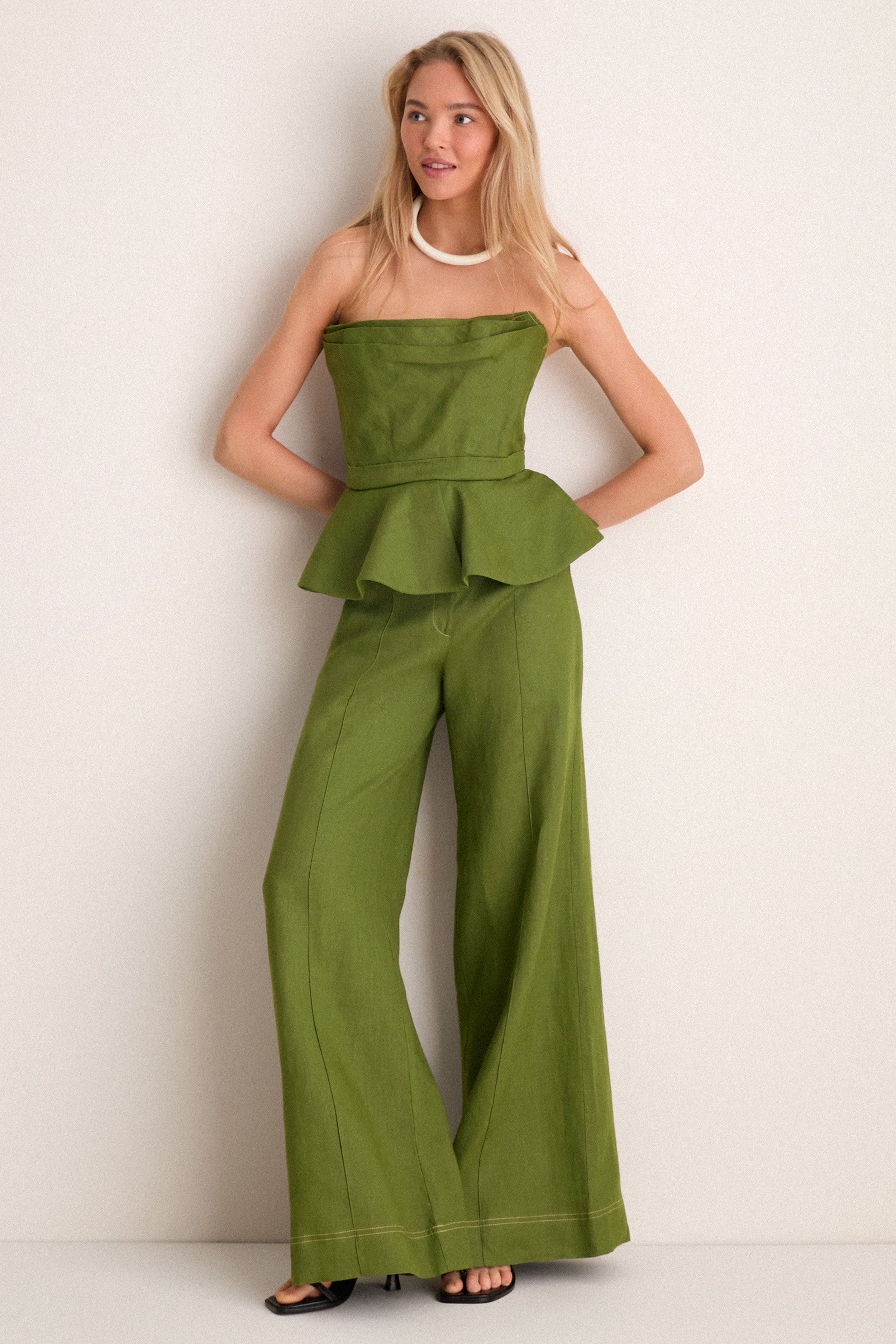 Person wearing Olive Green Vivir Pants, showcasing a classic, high-waisted, wide-leg design. Paired with a matching top for an effortless, high-end, fun ensemble.