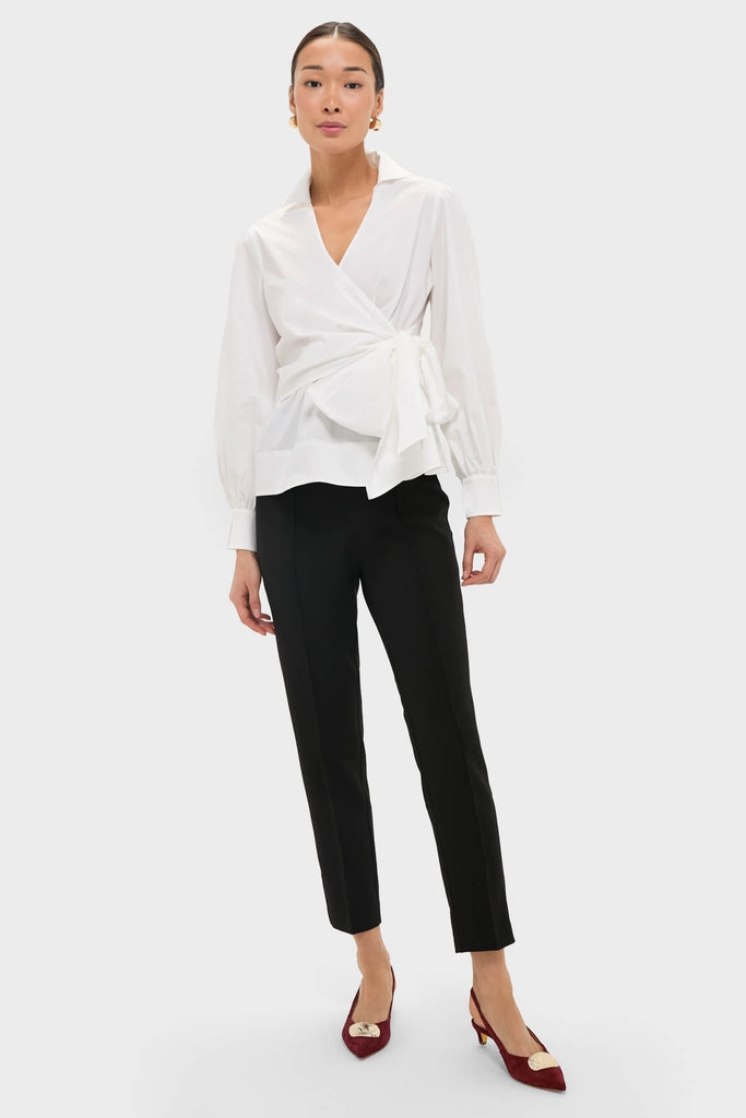 Model wearing Black Audrey Pants with a classic, slimming fit, styled effortlessly with a white wrap blouse and burgundy slingback shoes, exuding high-end, fun sophistication.