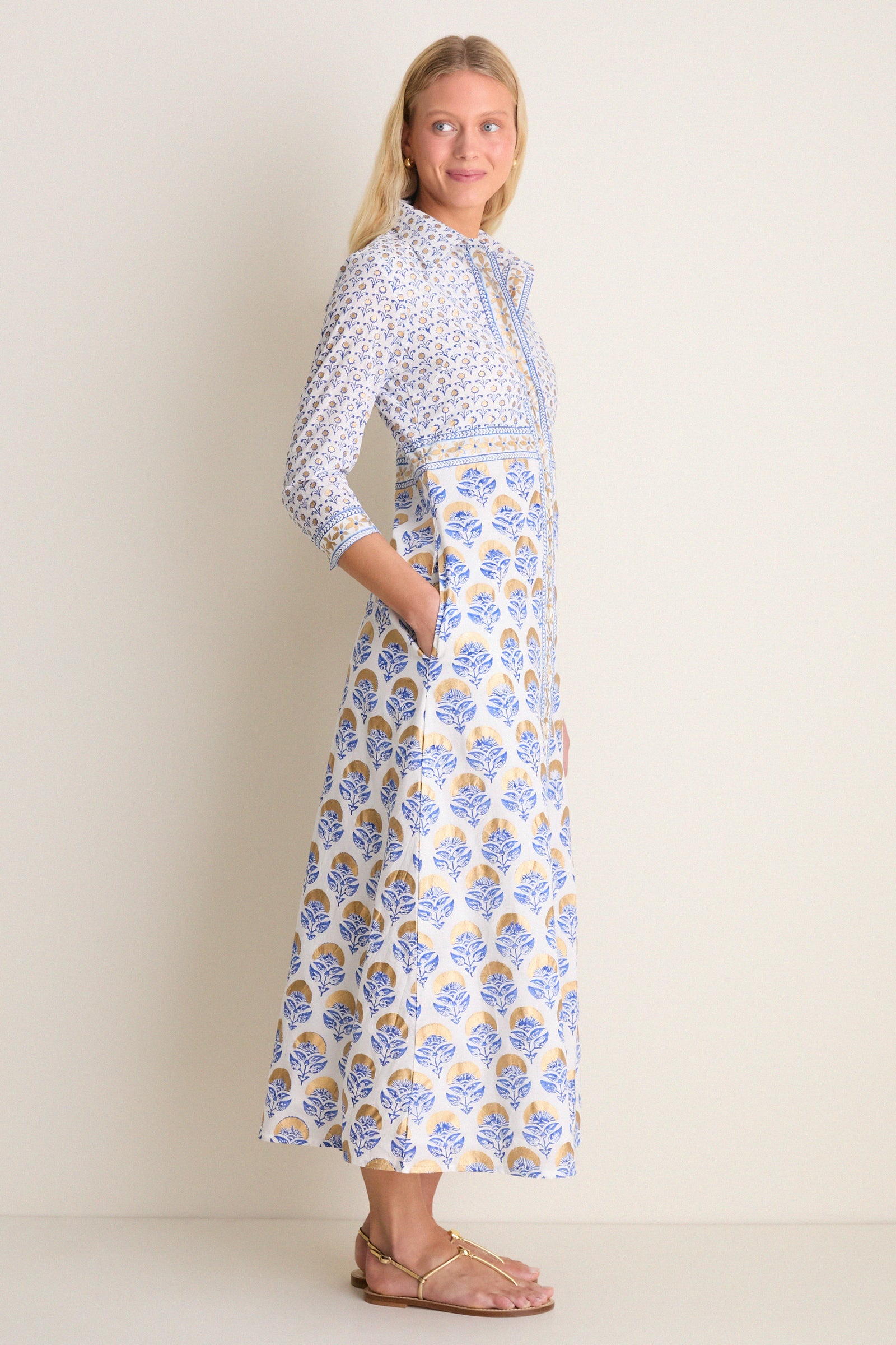 Young woman in profile wearing the Arbor Blue Maxi Shirt Dress; a classic, high-end cotton voile piece with an effortless floral print and gold accents.