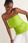 Young woman in a classic, high-end Lime Felix Satin Strapless Top with fold-over neckline, exemplifying effortless style and fun elegance, paired with chic white pants.