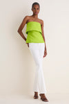 Model in classic, effortless Lime Felix Satin Strapless Top with fold-over neckline, paired with high-end white jeans and heels for a fun, chic look.