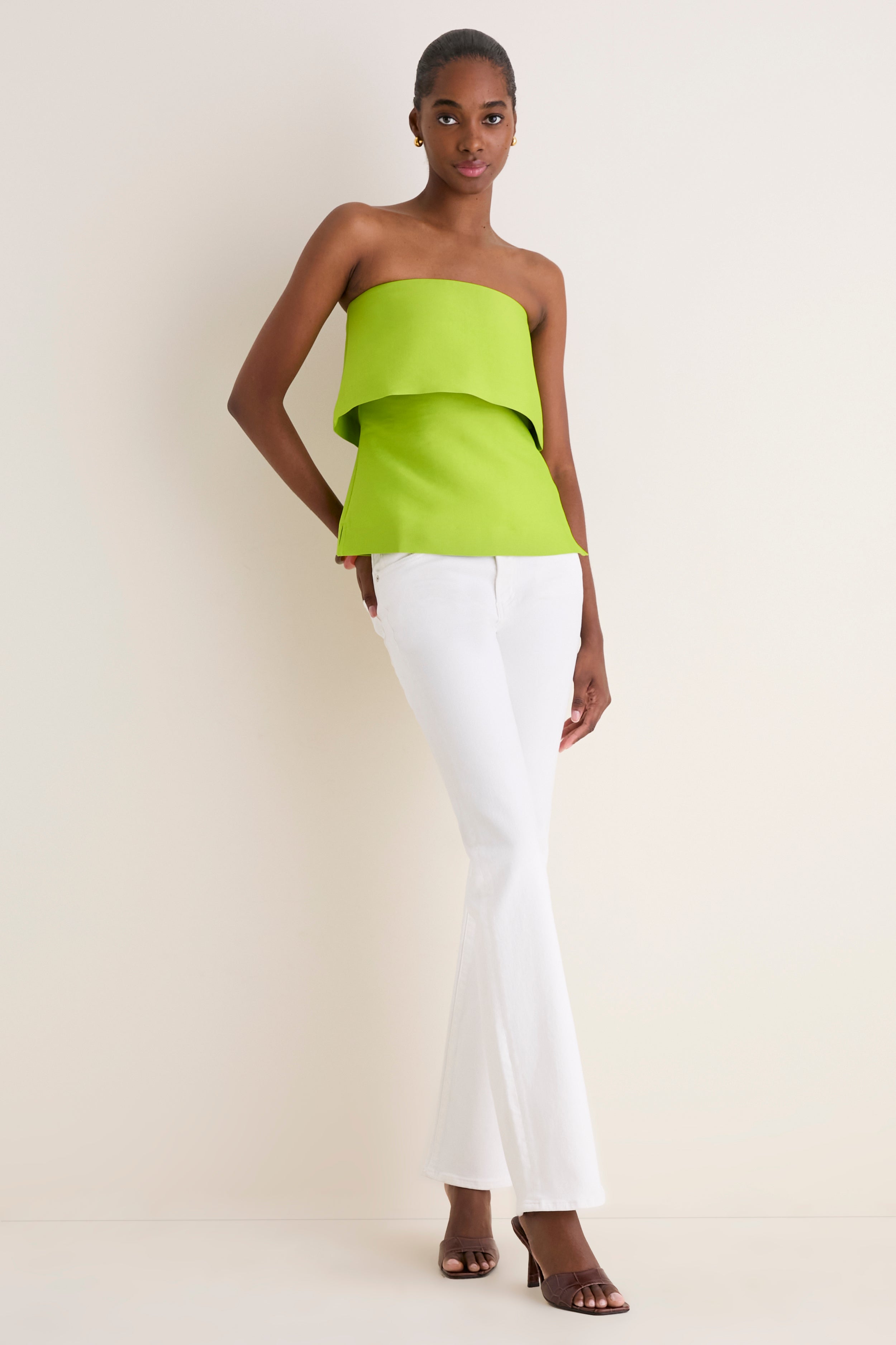 Model in classic, effortless Lime Felix Satin Strapless Top with fold-over neckline, paired with high-end white jeans and heels for a fun, chic look.