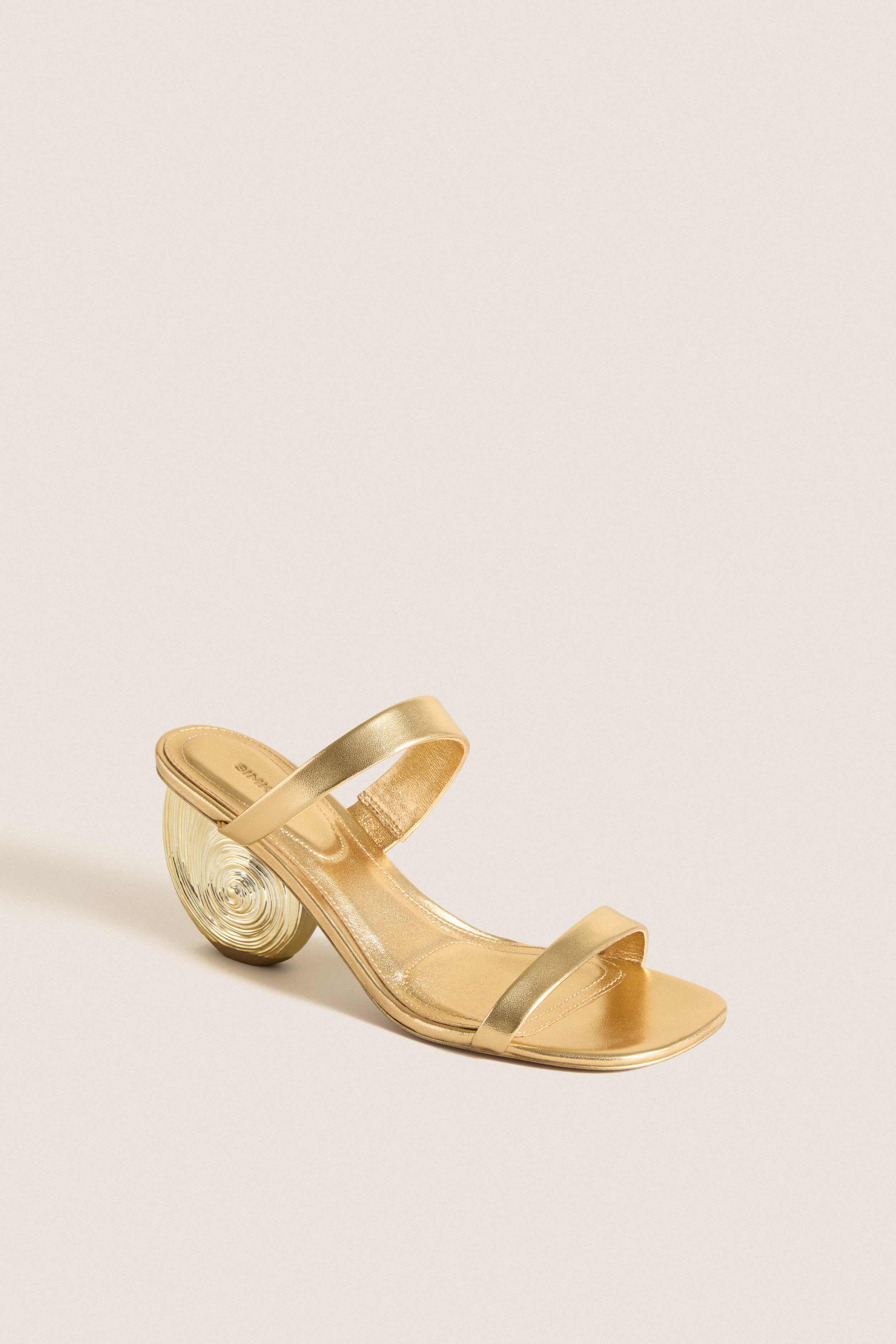 Gold Marion Metallic Shell Heels: Classic, effortless heeled sandal in metallic gold with square toe, dual straps, and sculptural swirl-patterned heel, epitomizing high-end fun.