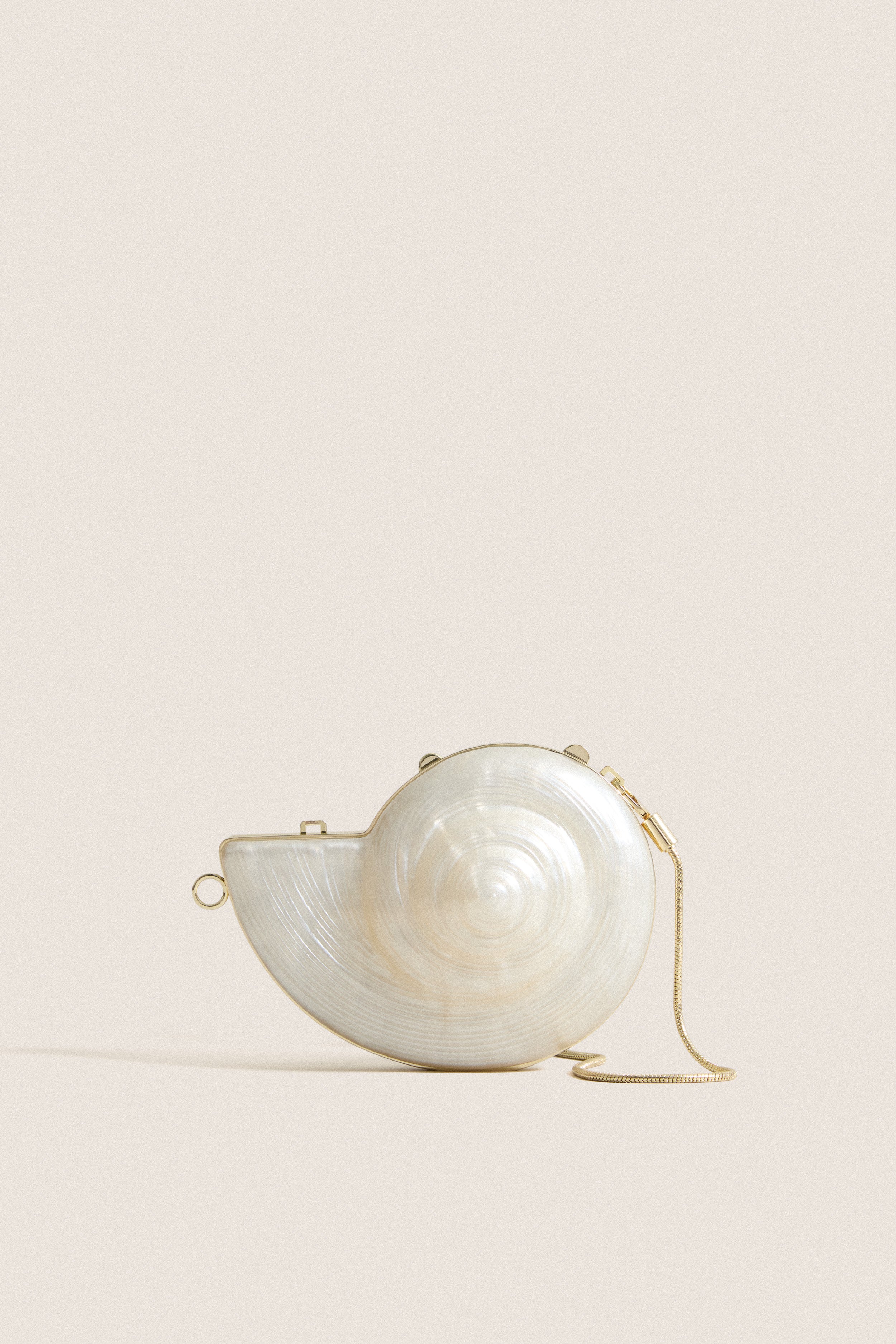 Pearl Marion Shell Clutch, a high-end, fun accessory with a nautilus shape, mother-of-pearl finish, gold trim, and chain, for an effortless, classic style.