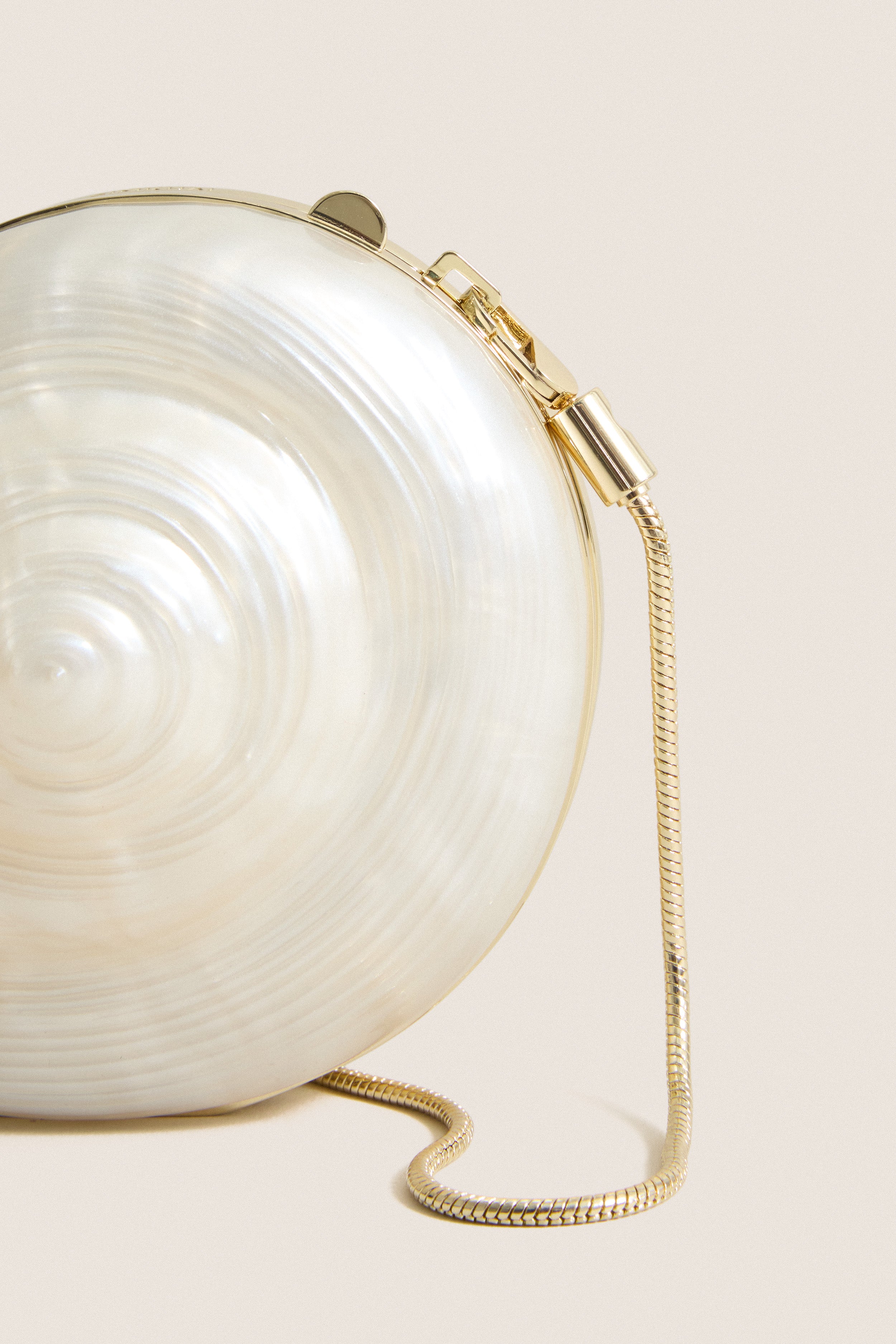 Pearl Marion Shell Clutch: A classic, high-end evening bag with a pearly swirl design, gold trim, and detachable chain, offering effortless elegance and fun versatility.