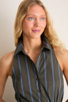 Young woman models the Huntington Stripe Romy Dress, a classic, sleeveless shirt dress with an effortless, high-end design featuring blue and gray stripes and subtle waist ruching.