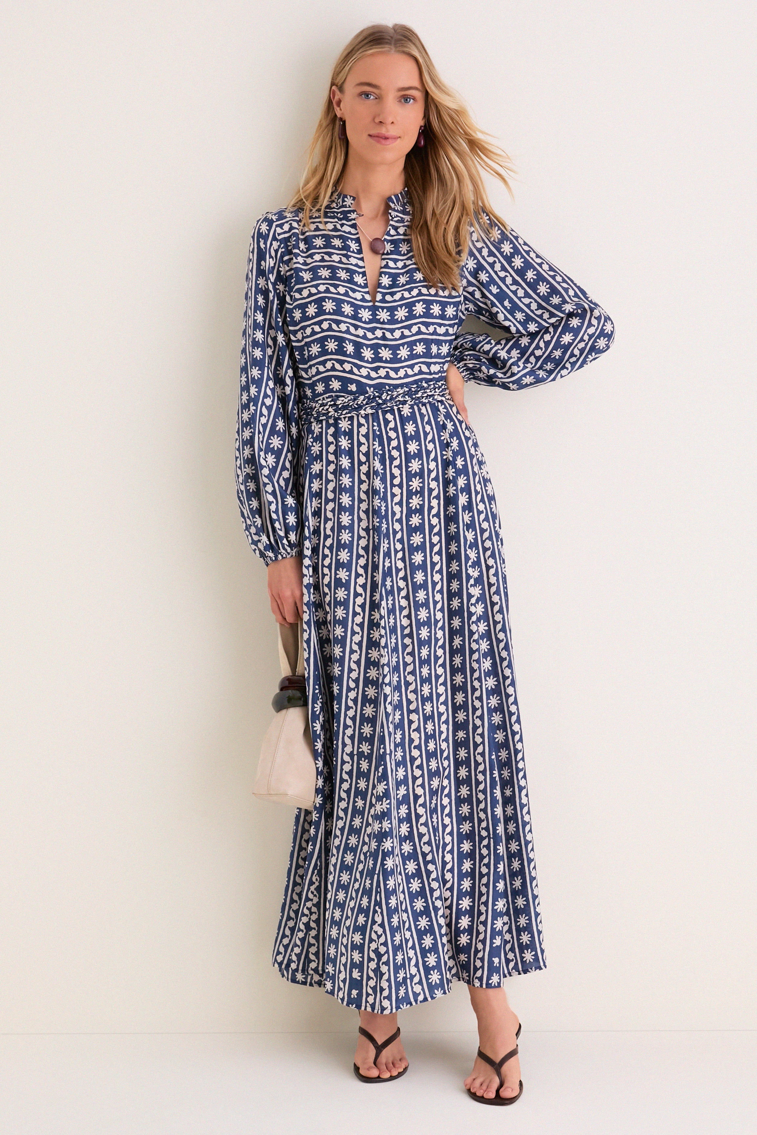 The Wave Wonder Nala Maxi Dress, a classic silk piece with a V-neck and billowy sleeves, captures effortless elegance, complemented by a fun beige handbag for a high-end look.