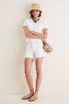 Woman in a classic, effortless summer outfit featuring the Green Mykonos Necklace, with lush malachite beads and a shell pendant, embodying a fun, high-end vibe.