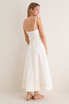 Woman models the classic Off White Fiona Dress, featuring an effortless fitted smocked bodice, A-line skirt, adjustable straps; paired with fun, high-end gold-tone sandals and hoop earrings.