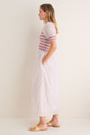 Woman in profile wearing the classic, effortless Poppy Half Drop White Madeline Nap Dress with puffed sleeves, smocked bodice, and fun floral motifs; styled with high-end accessories.