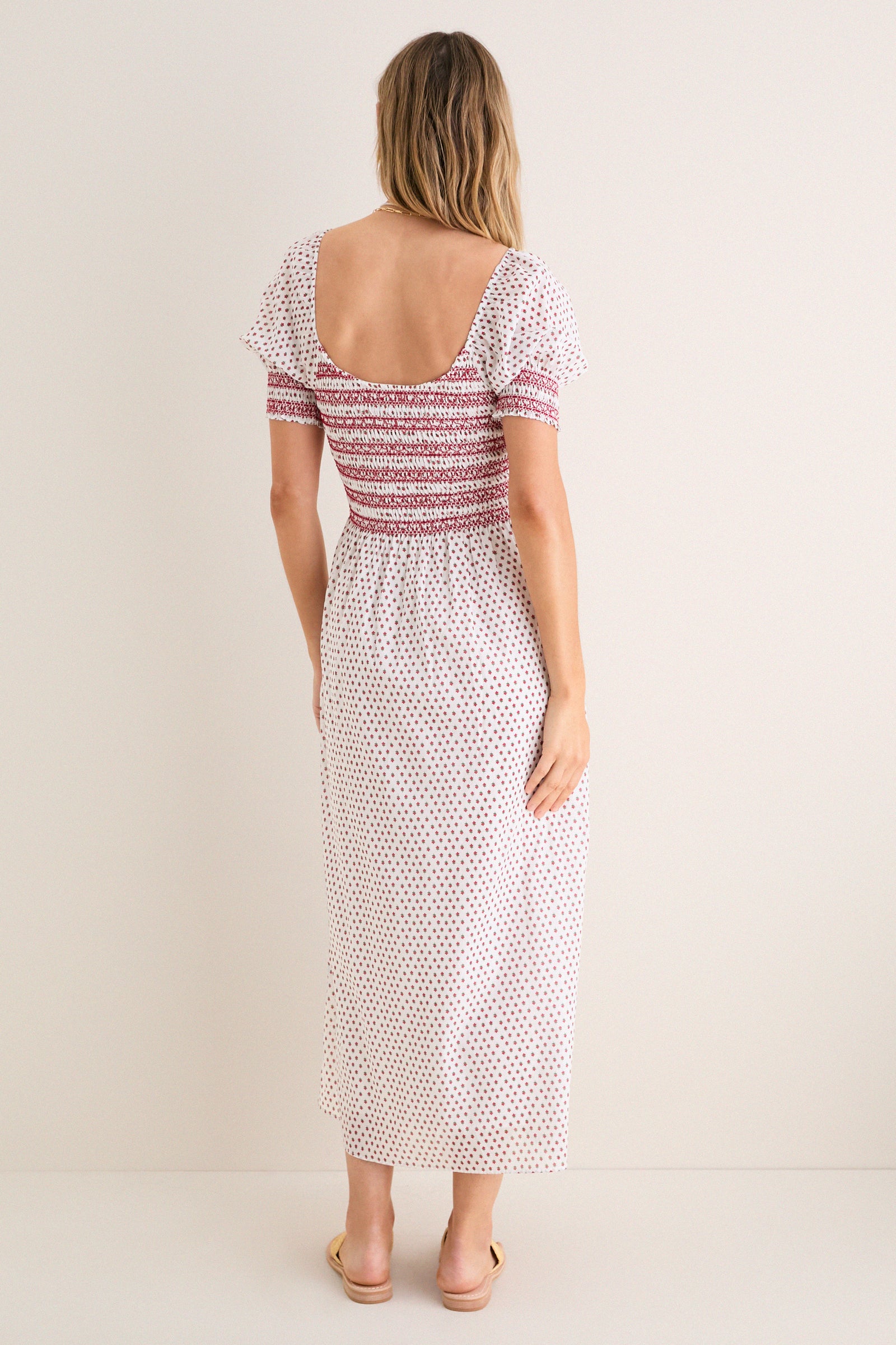 Model wearing the classic Poppy Half Drop White Madeline Nap Dress with a scooped back, flutter sleeves, and smocked bodice, embodying effortless, high-end style.
