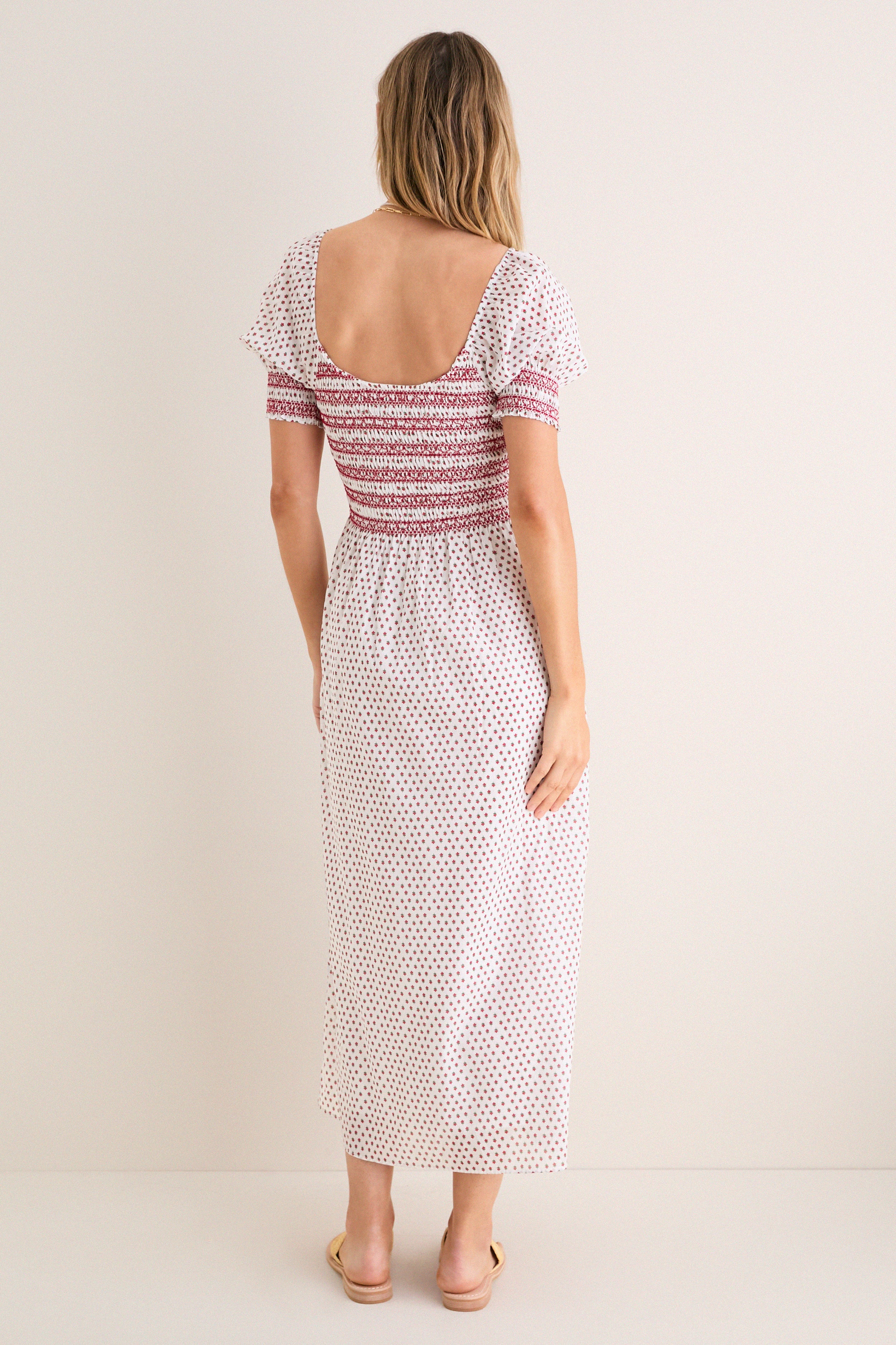 Model wearing the classic Poppy Half Drop White Madeline Nap Dress with a scooped back, flutter sleeves, and smocked bodice, embodying effortless, high-end style.