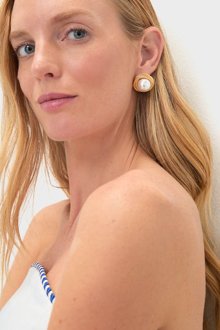 Young woman wearing Gold Gigi Earrings; faux pearl framed by textured gold, offering a classic, effortless, high-end look. Perfect for a fun, stylish getaway ensemble.