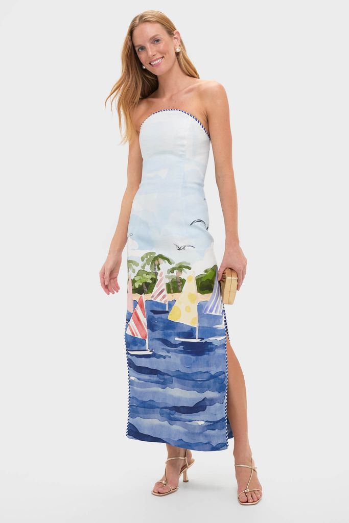 Woman models a classic strapless dress, pairing it with effortlessly chic Gold Gigi Earrings featuring faux pearls, embodying a fun, high-end, getaway-ready style.