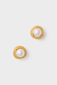 Gold Gigi Earrings featuring classic round faux pearls encased in textured gold-tone borders. Effortless and fun, these high-end earrings exude a vintage-inspired charm.