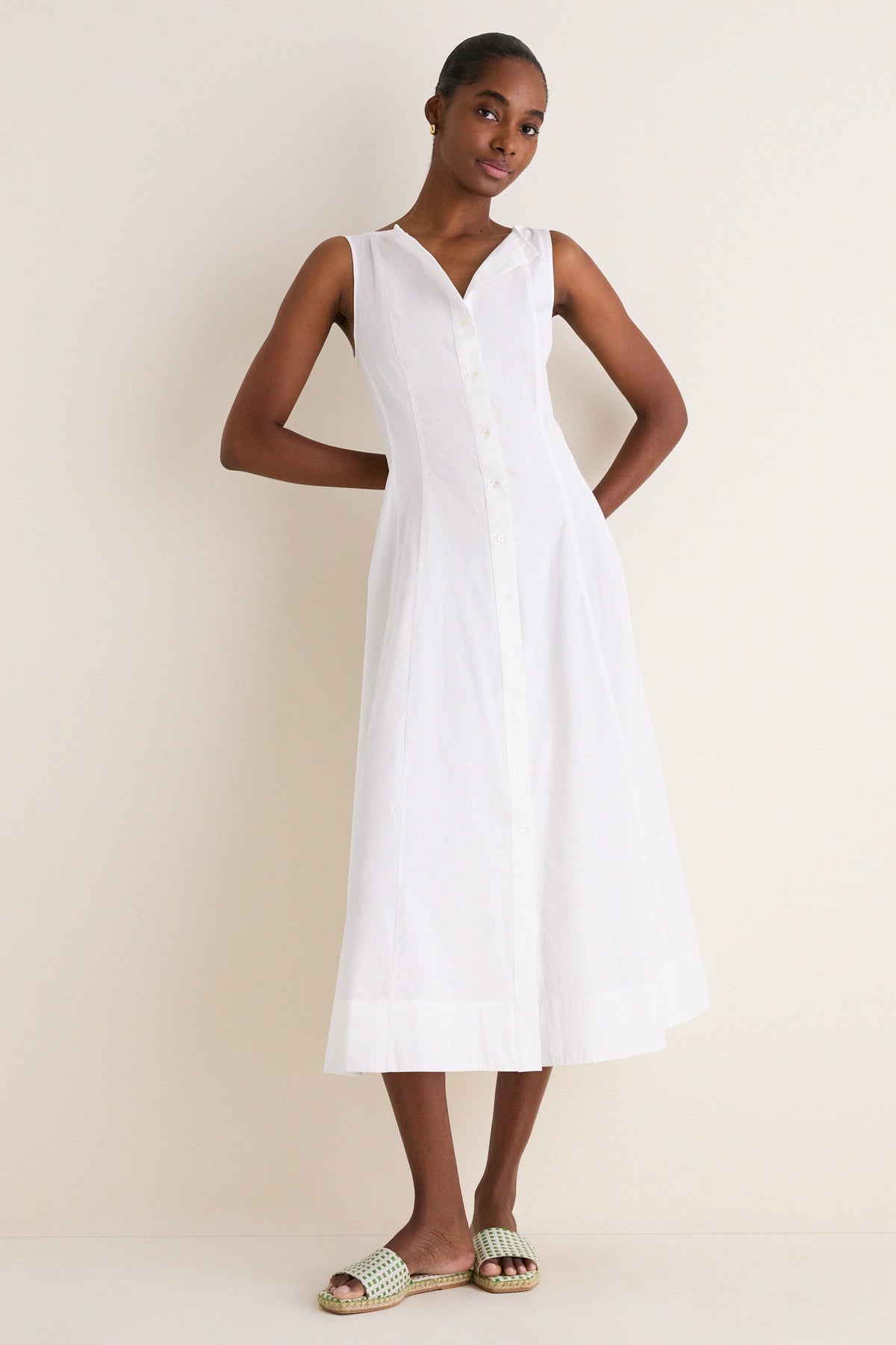 A slim woman models a White Cotton Boat Neck Dress, exuding effortless elegance with its classic sleeveless design, ideal for high-end, fun, warm-weather styling.