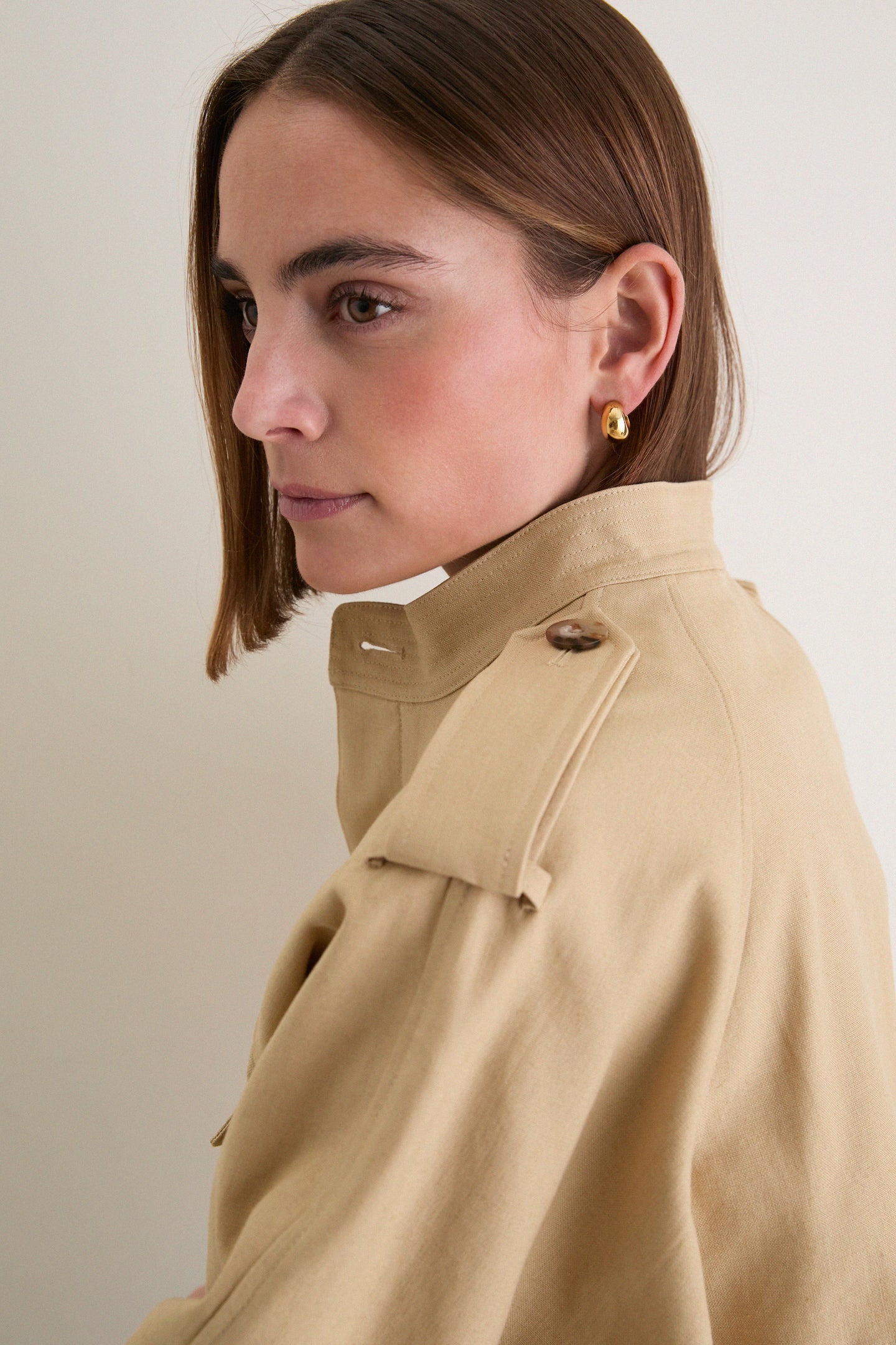 Side profile of a person wearing a classic camel cotton field jacket with buttoned epaulet, showcasing effortless style and high-end, fun utility.
