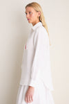Classic Oxford White Linen Button Down modeled side-profile, showcasing relaxed fit, point collar, shell buttons, and embroidered detail on chest pocket for an effortless, high-end style.