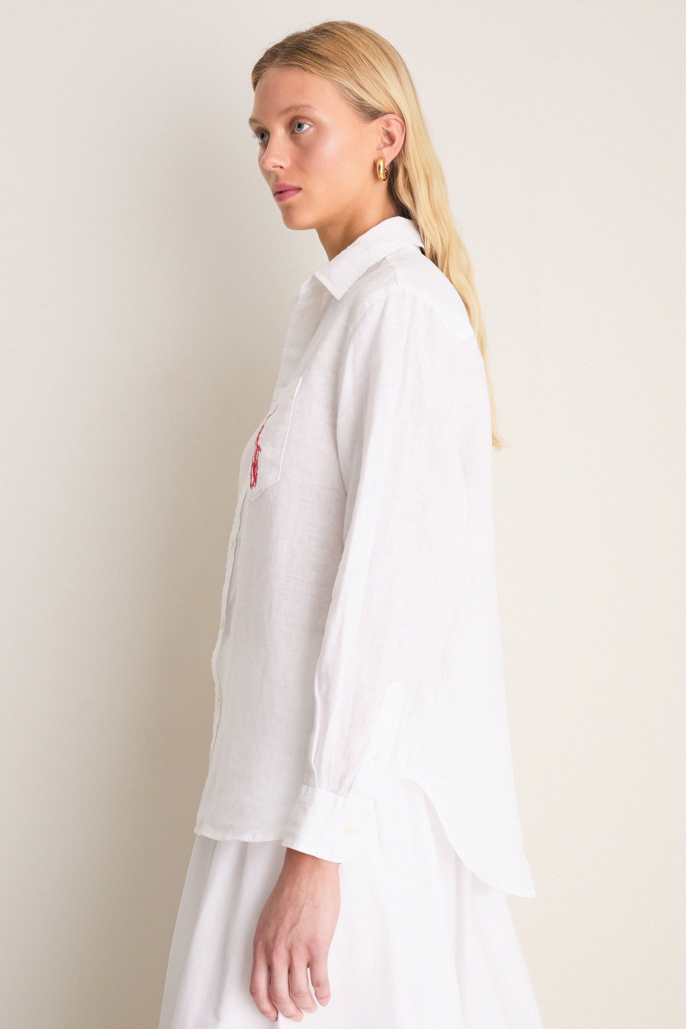 Classic Oxford White Linen Button Down modeled side-profile, showcasing relaxed fit, point collar, shell buttons, and embroidered detail on chest pocket for an effortless, high-end style.